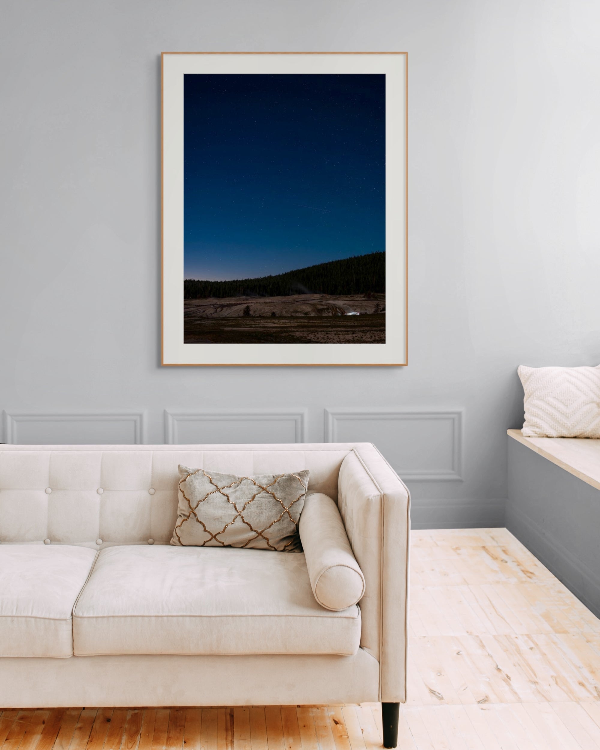 Framed artwork above a beige sofa in a room with light gray walls.