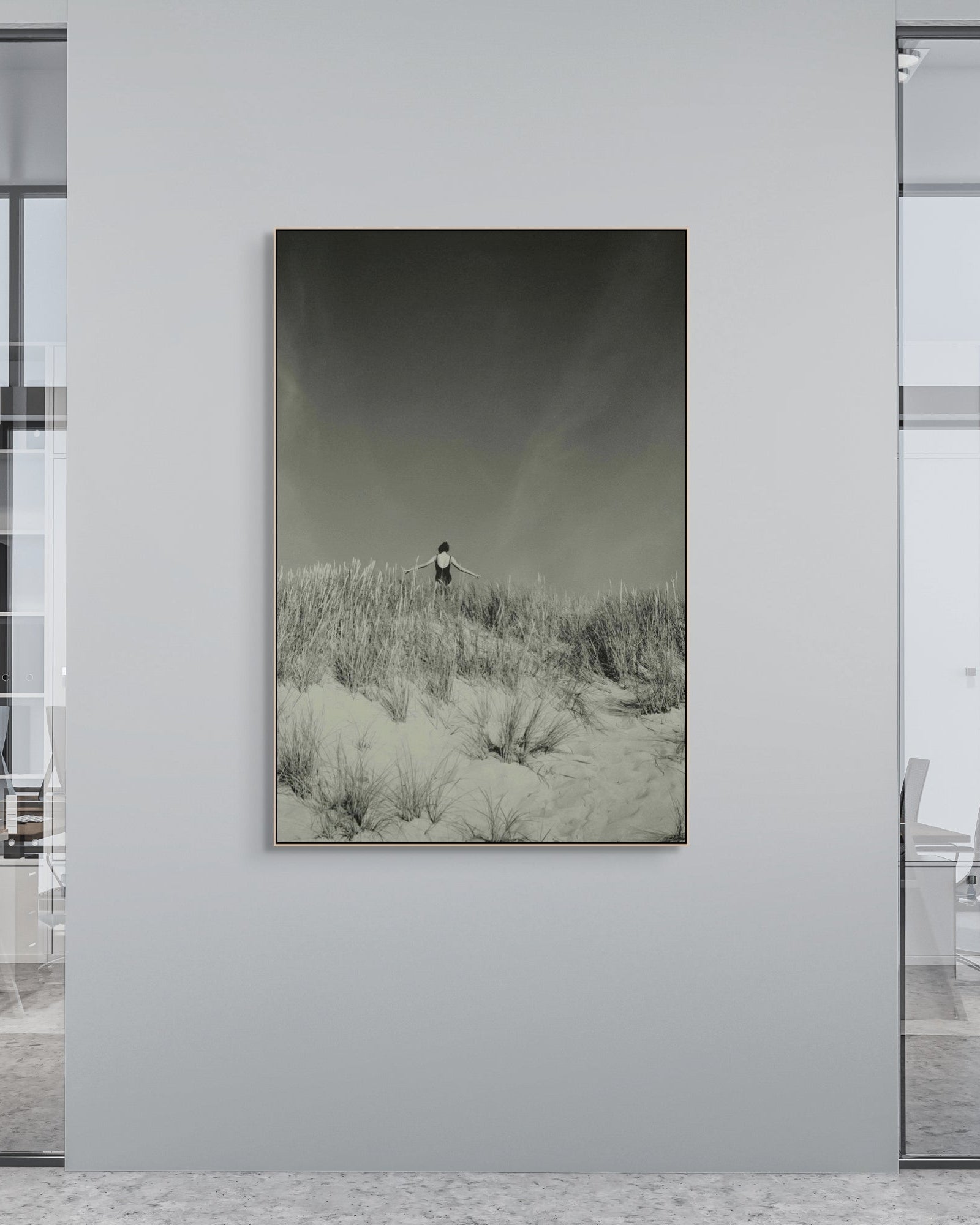 Artistic landscape print on a wall in an office setting with glass walls and chairs.