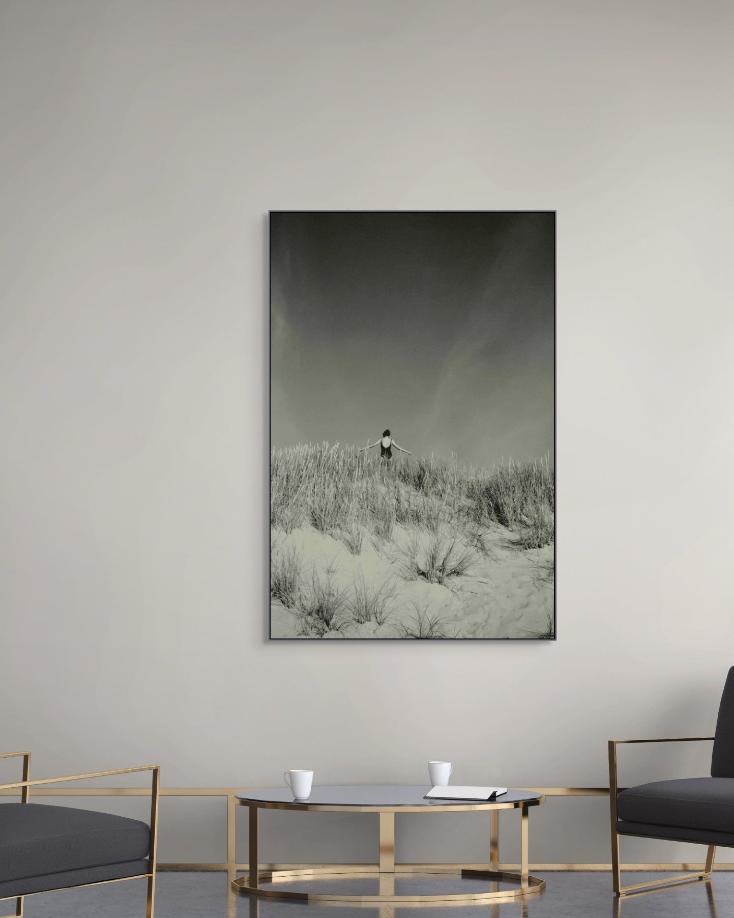 Framed landscape print on a wall above a modern living room setup with chairs and a table.