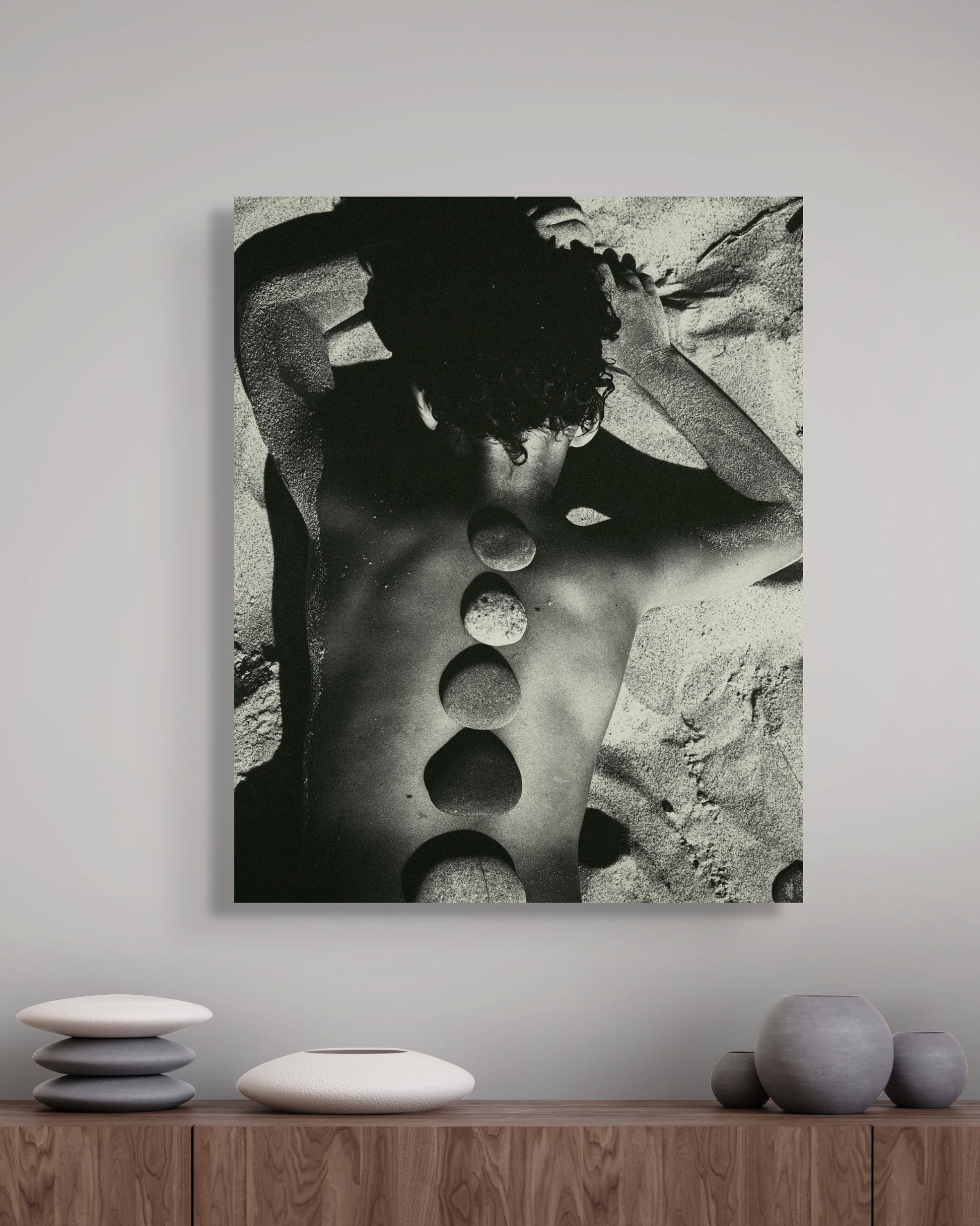 Metal print of a black and white abstract art piece on a wall above a wooden shelf with decorative items.