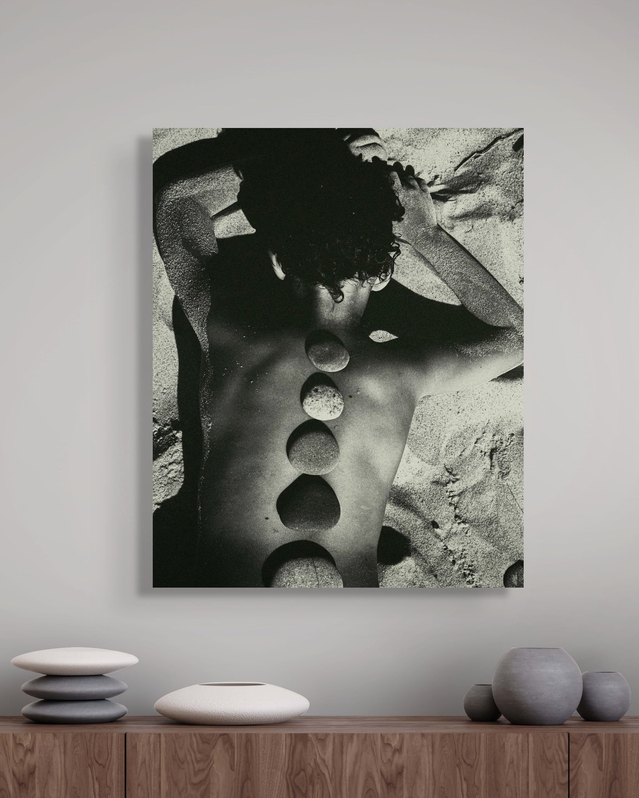 Metal print of a black and white abstract art piece on a wall above a wooden shelf with decorative items.