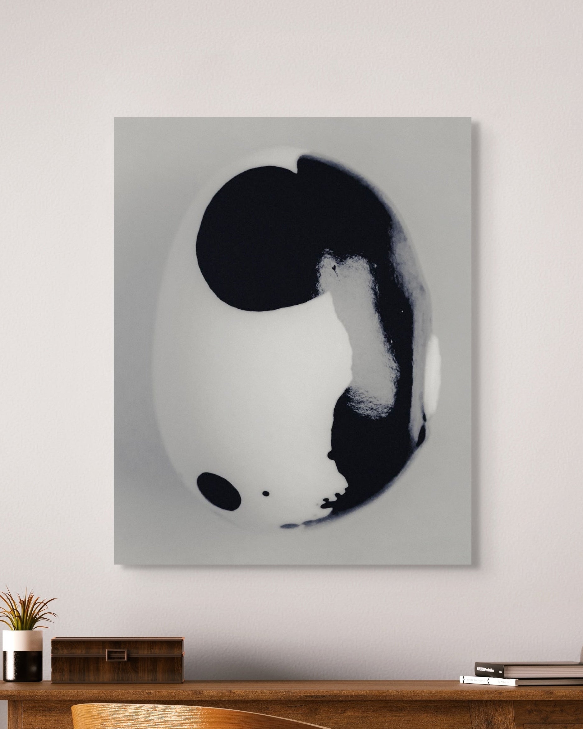Abstract art piece with black and white shapes on a gray background in a modern interior setting.