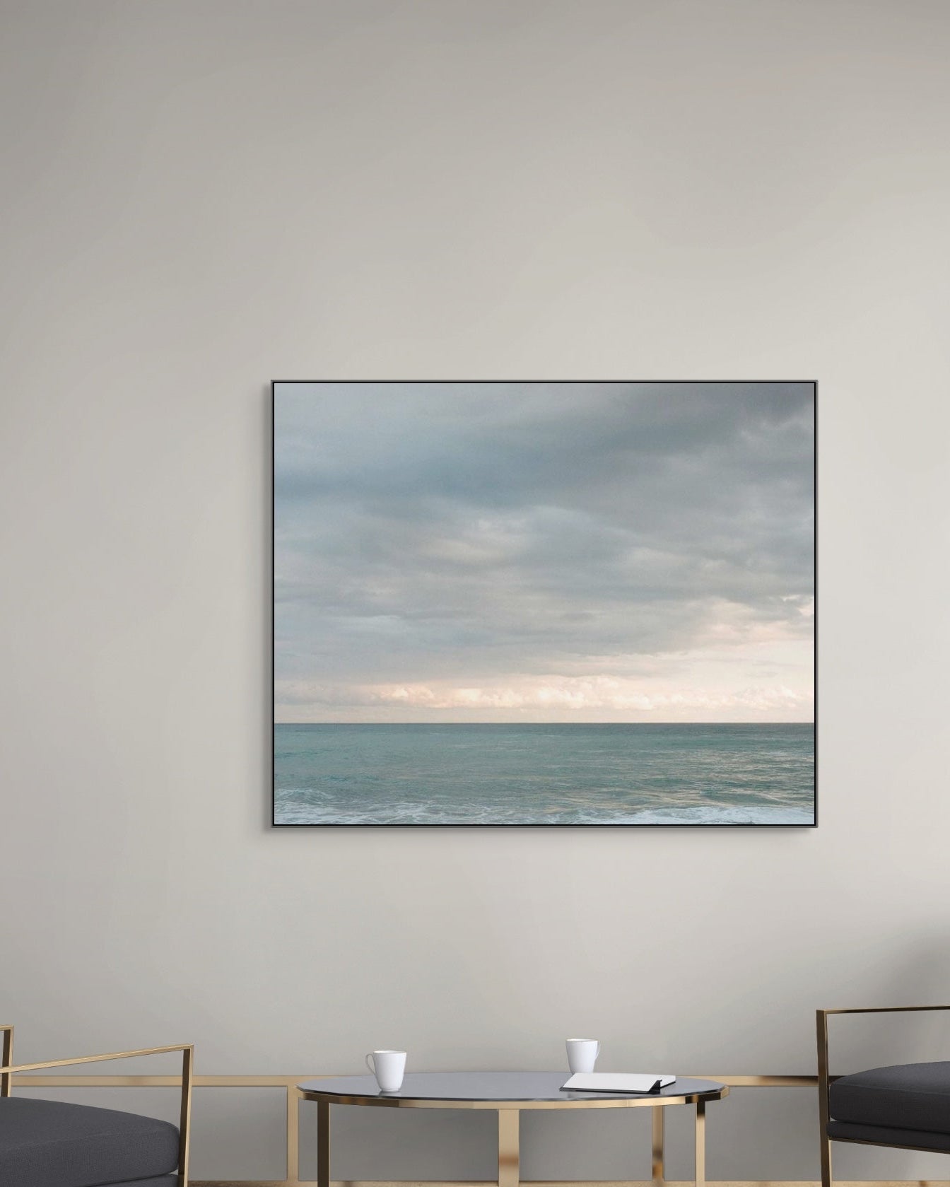Modern living room with a large metal print displaying an ocean scene, flanked by two gray chairs.