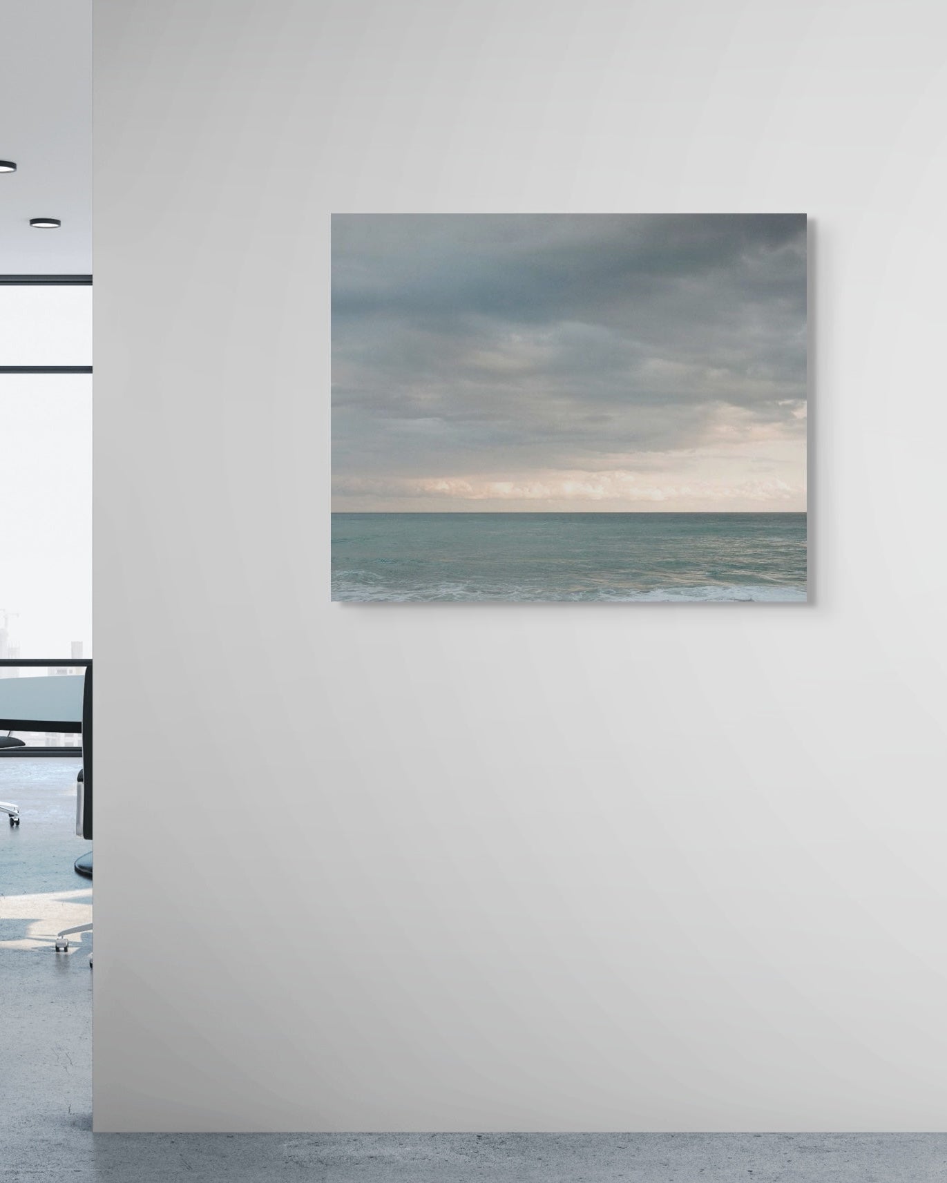 Metal print of a beach scene with clouds on a wall in an office setting.