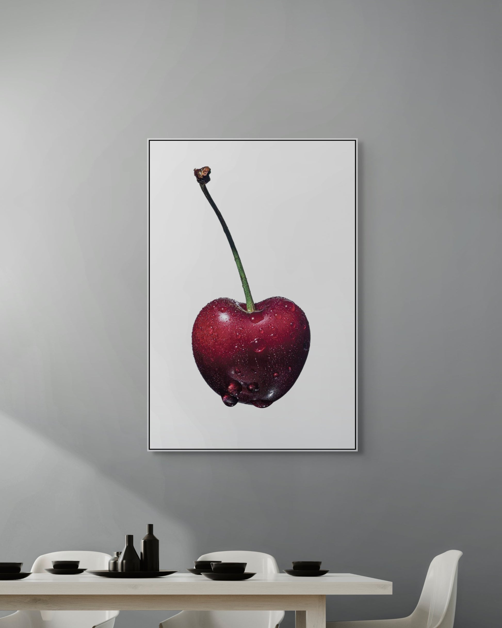 Framed artwork of a cherry on a gray wall above a dining table.