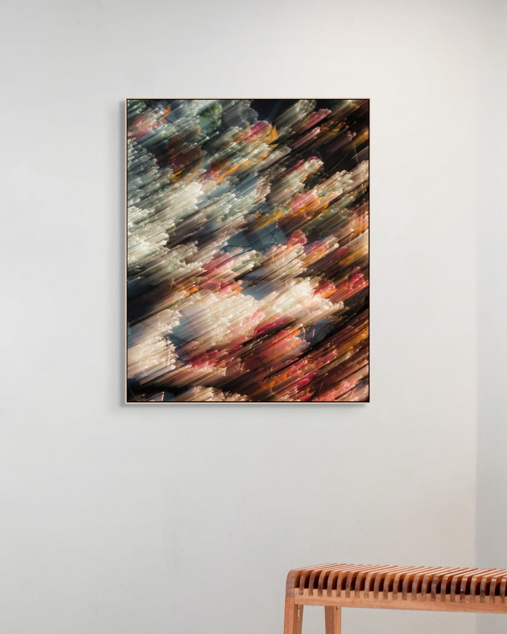 Abstract print on a white wall with a wooden bench below