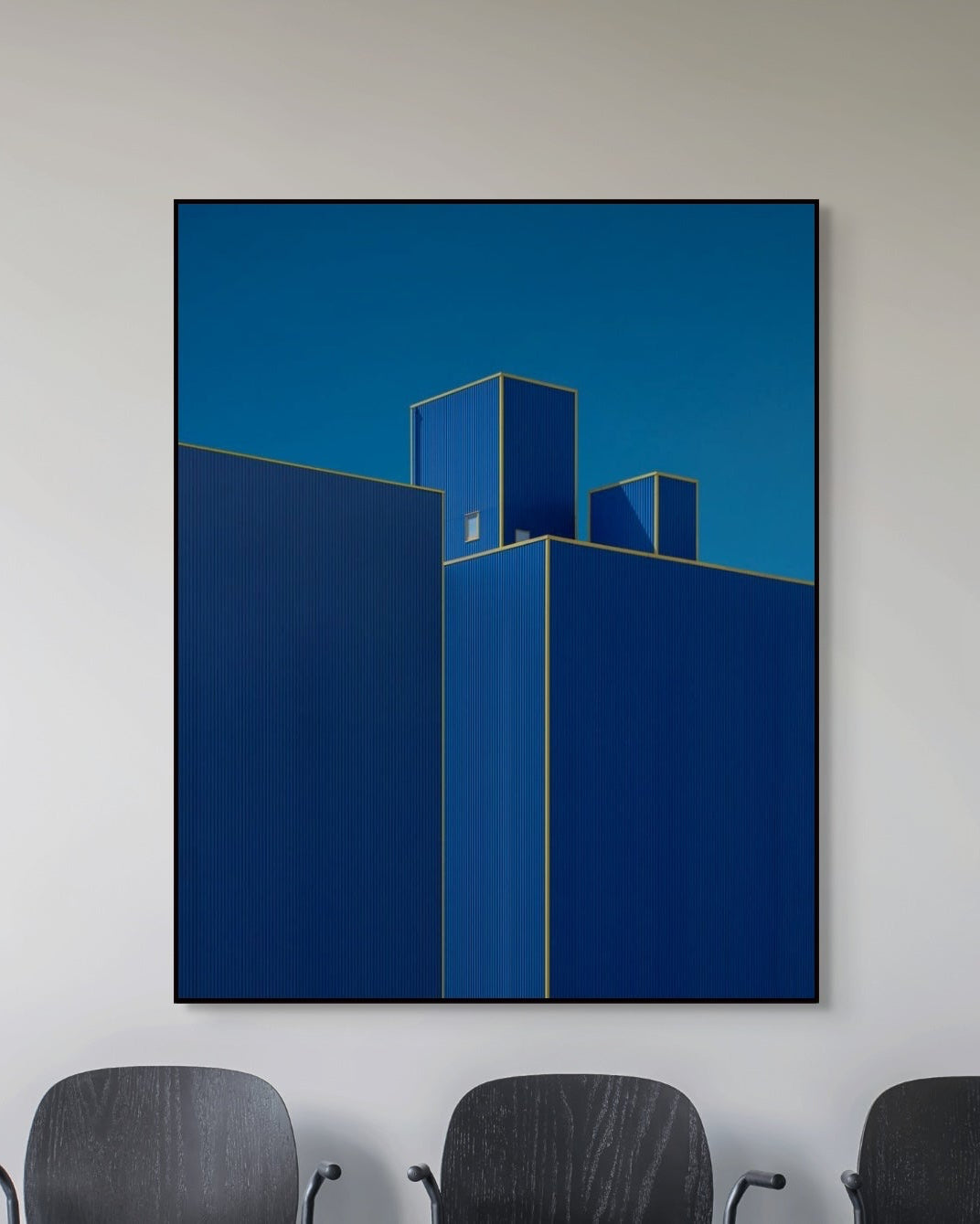 Abstract blue artwork on a white wall with chairs in the foreground