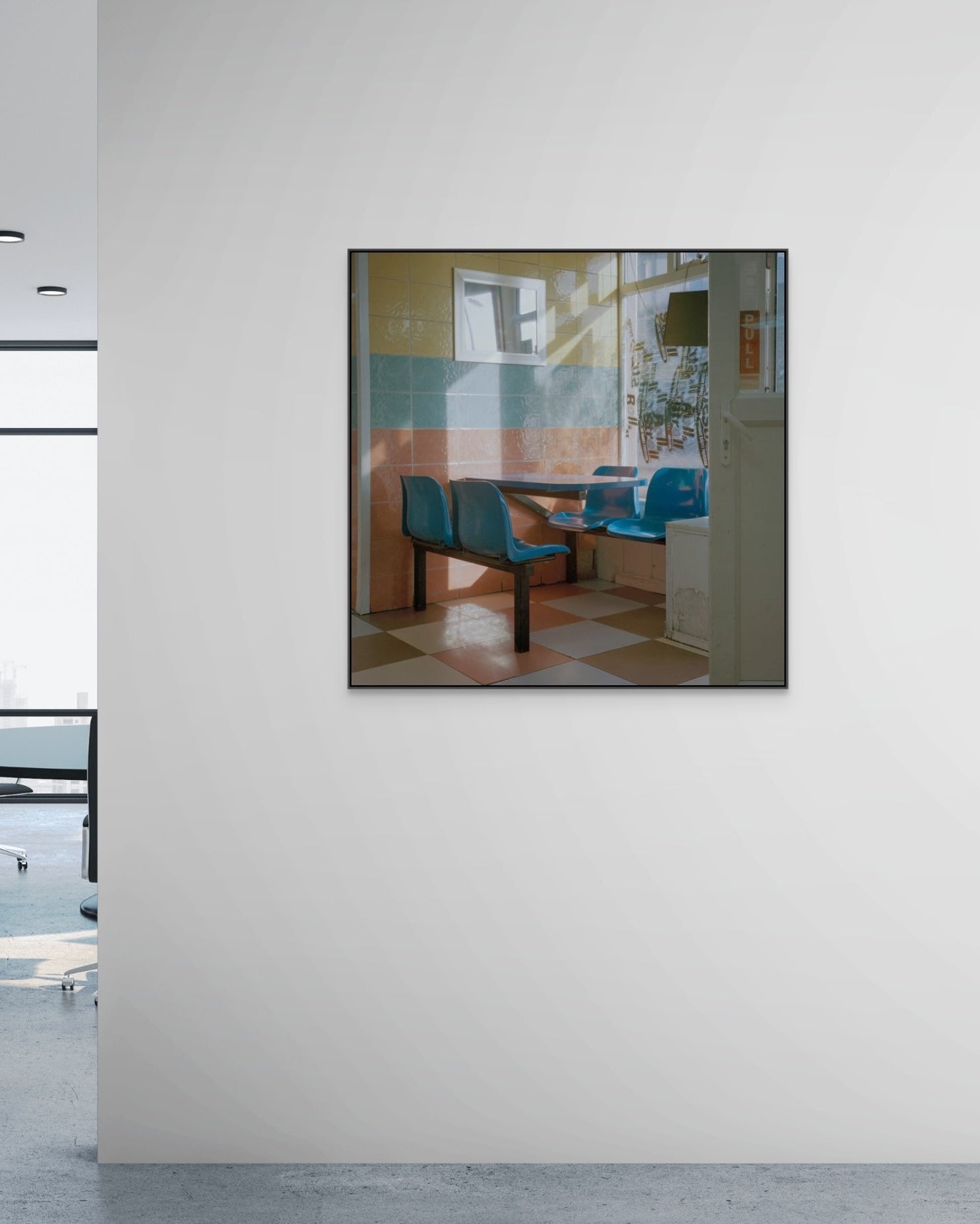 Framed photograph of a dining area with blue chairs on a white wall.