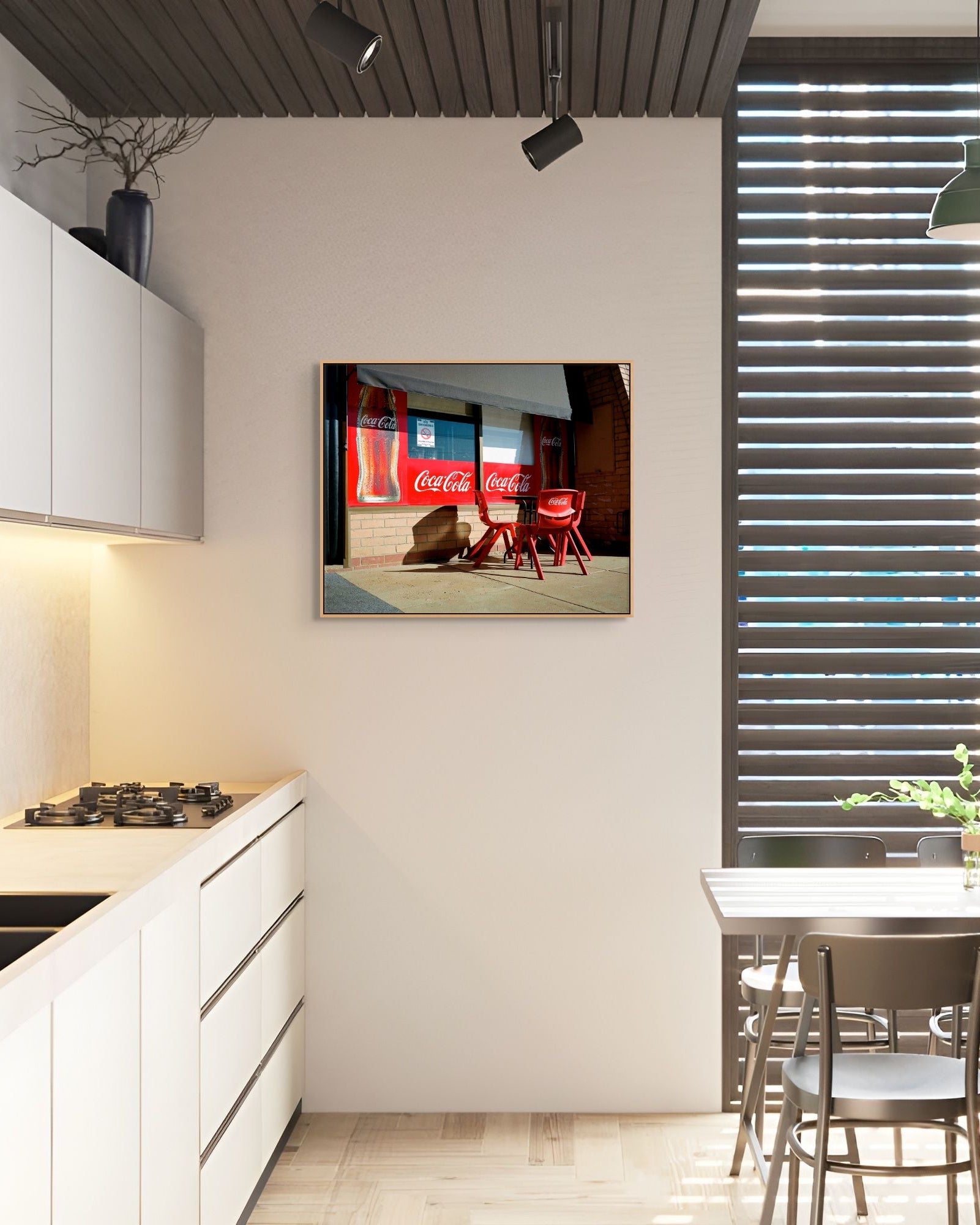 Framed Coca-Cola storefront photograph by Mark Forbes hanging on a neutral wall in a modern kitchen with light cabinetry and slatted window.