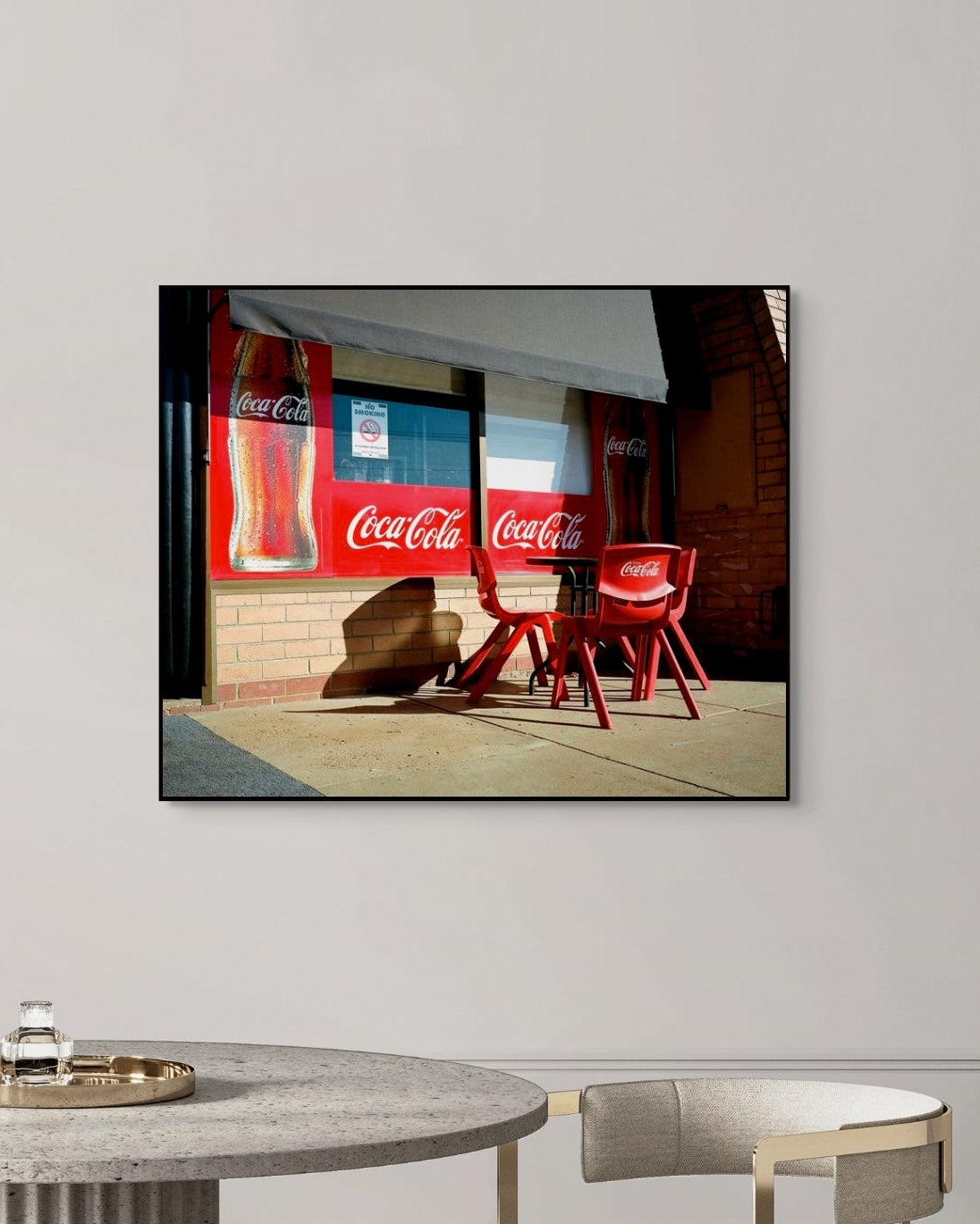 Framed artwork of Coca-Cola advertisement on a wall outside a shop.