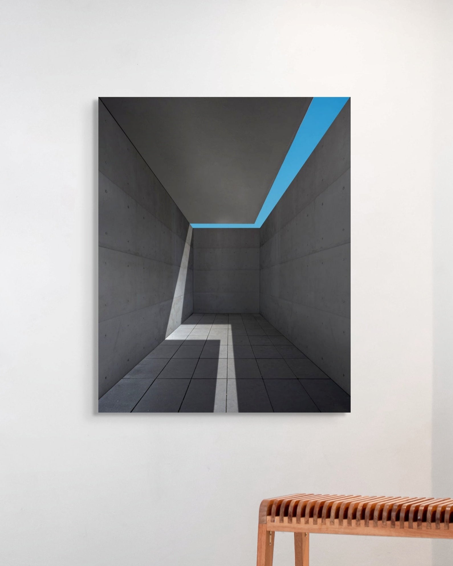 Abstract art print of a geometric design on a wall with a wooden bench below.
