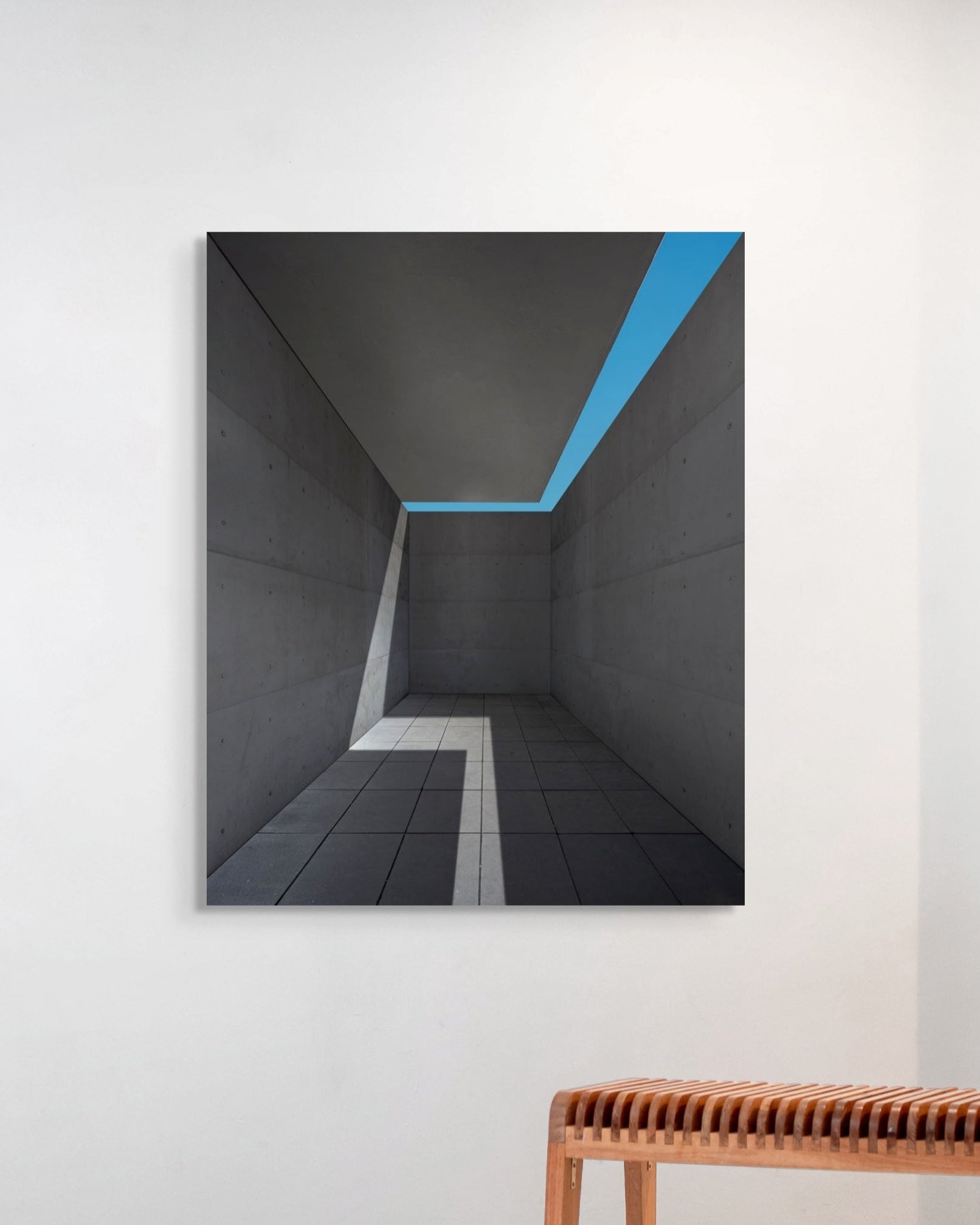Abstract art print of a geometric design on a wall with a wooden bench below.
