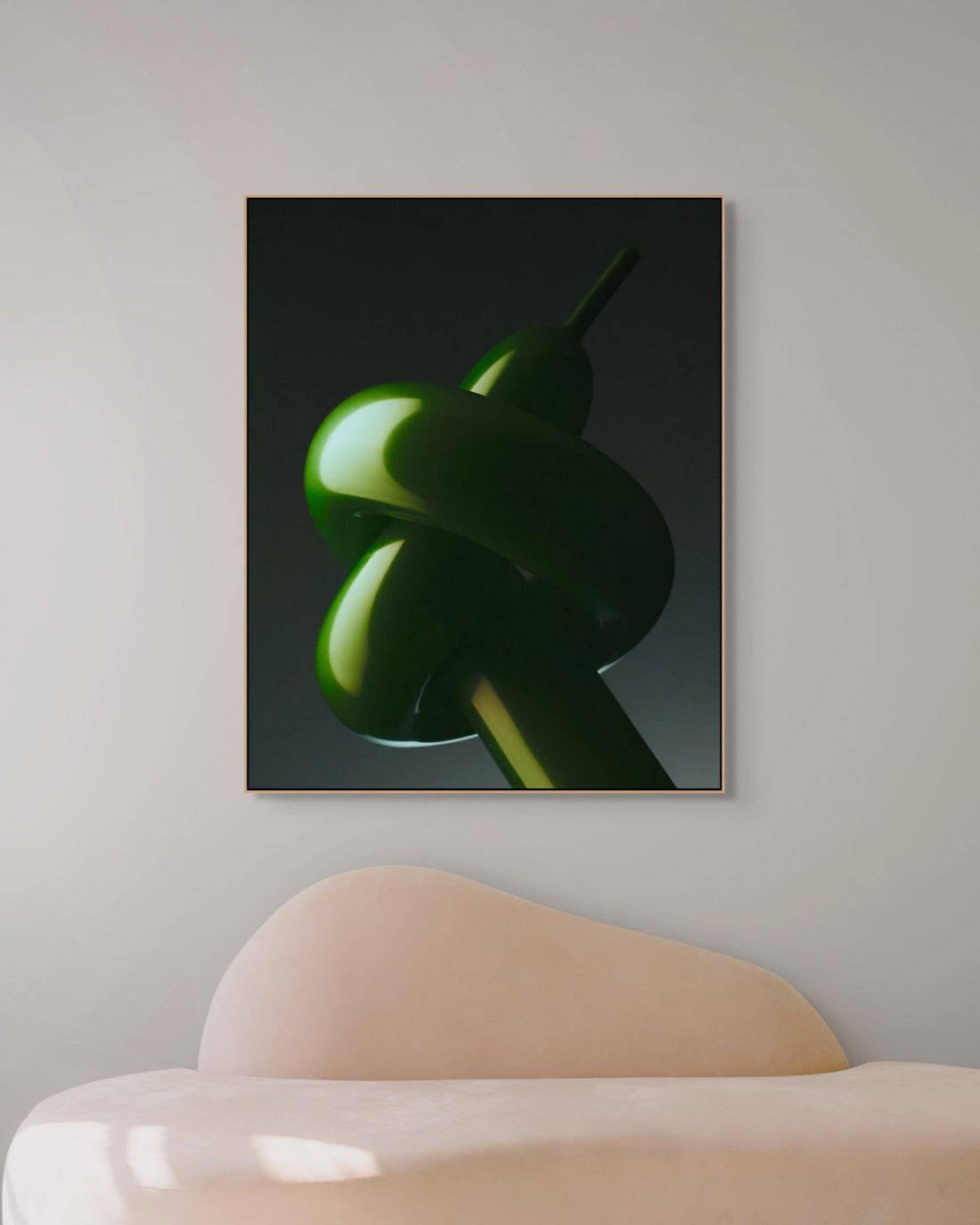 Framed artwork of a green abstract shape on a gray wall above a modern chair.