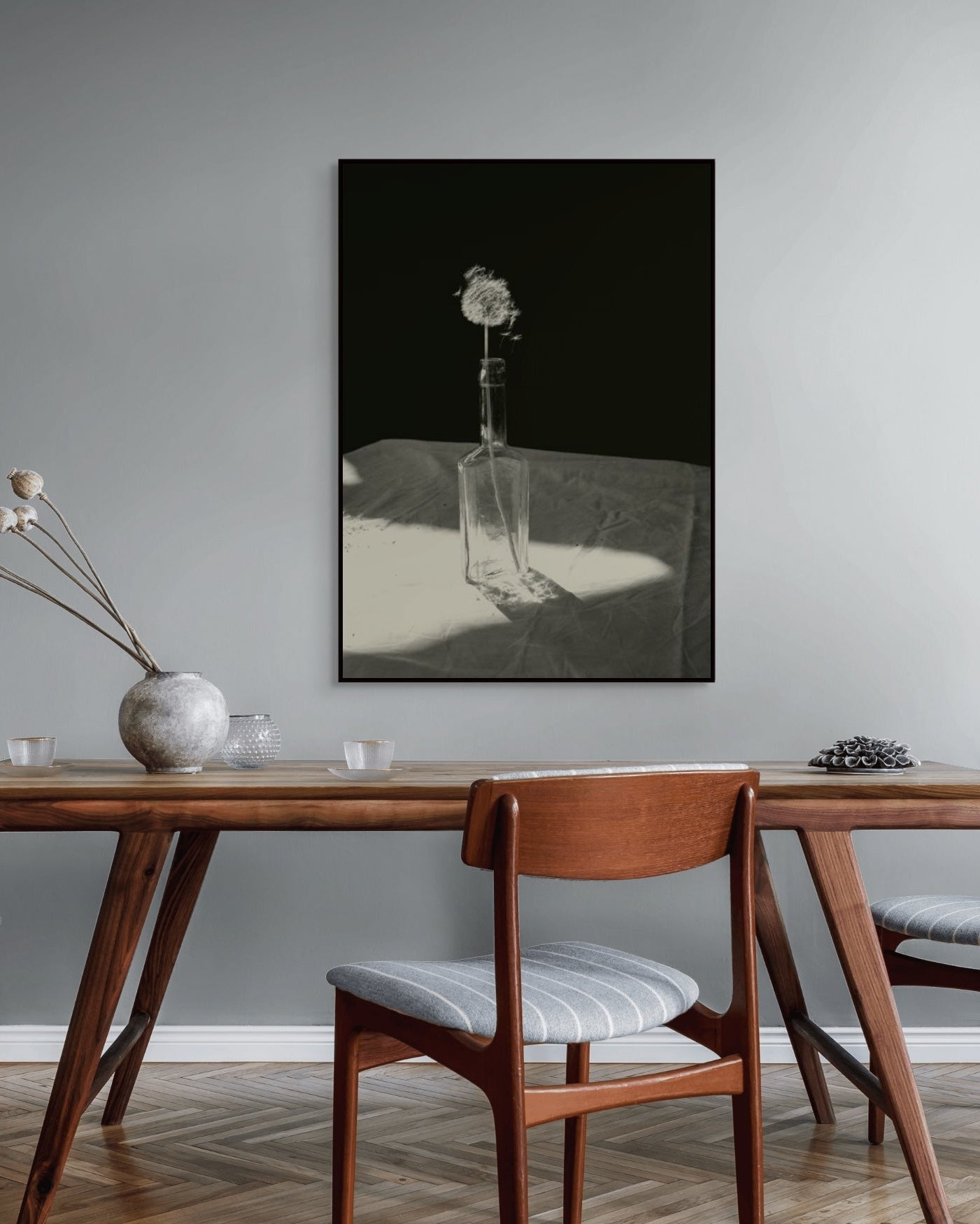 Dining room with wooden table and chairs, featuring a framed black and white artwork on the wall.
