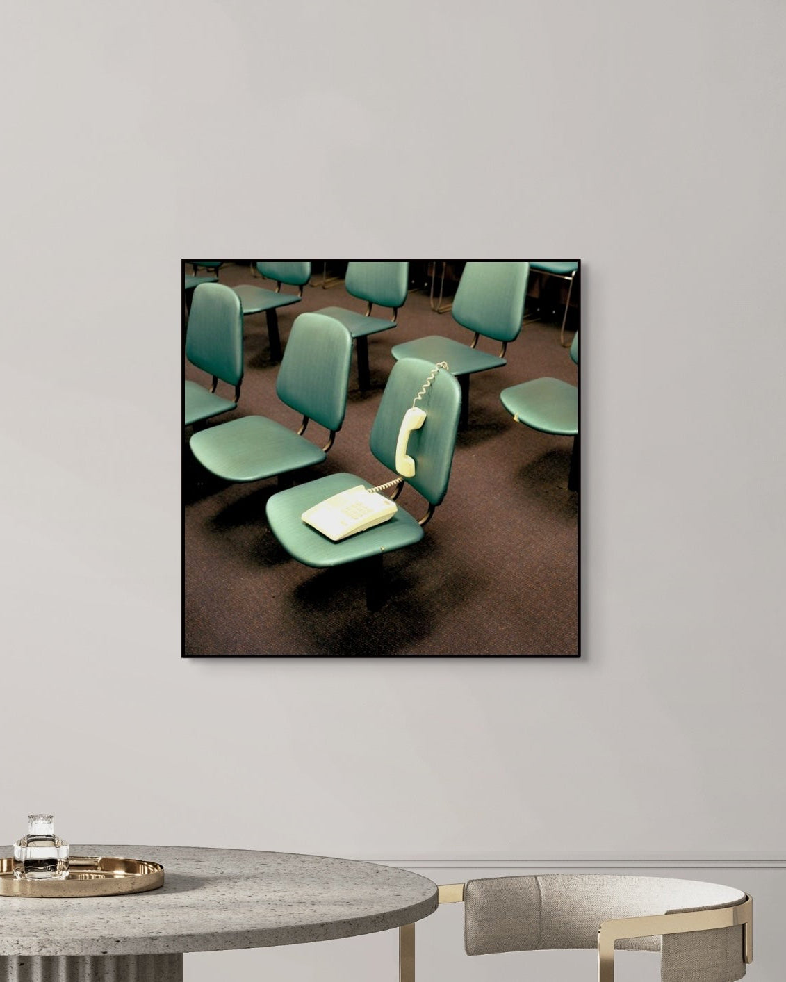Framed photograph of a vintage interior with green chairs on a white wall above a table.
