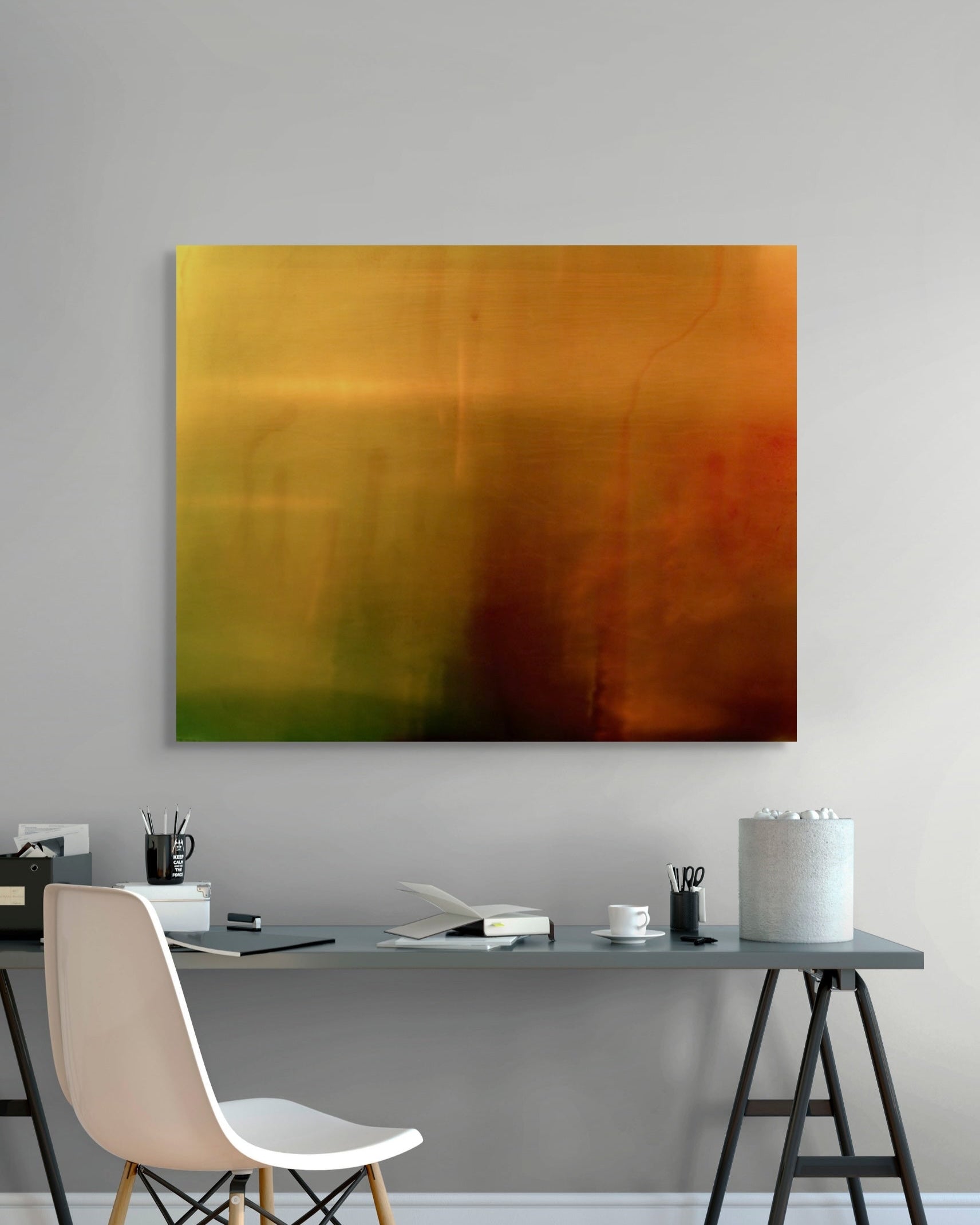 Abstract print on a gray wall above a desk with office supplies.