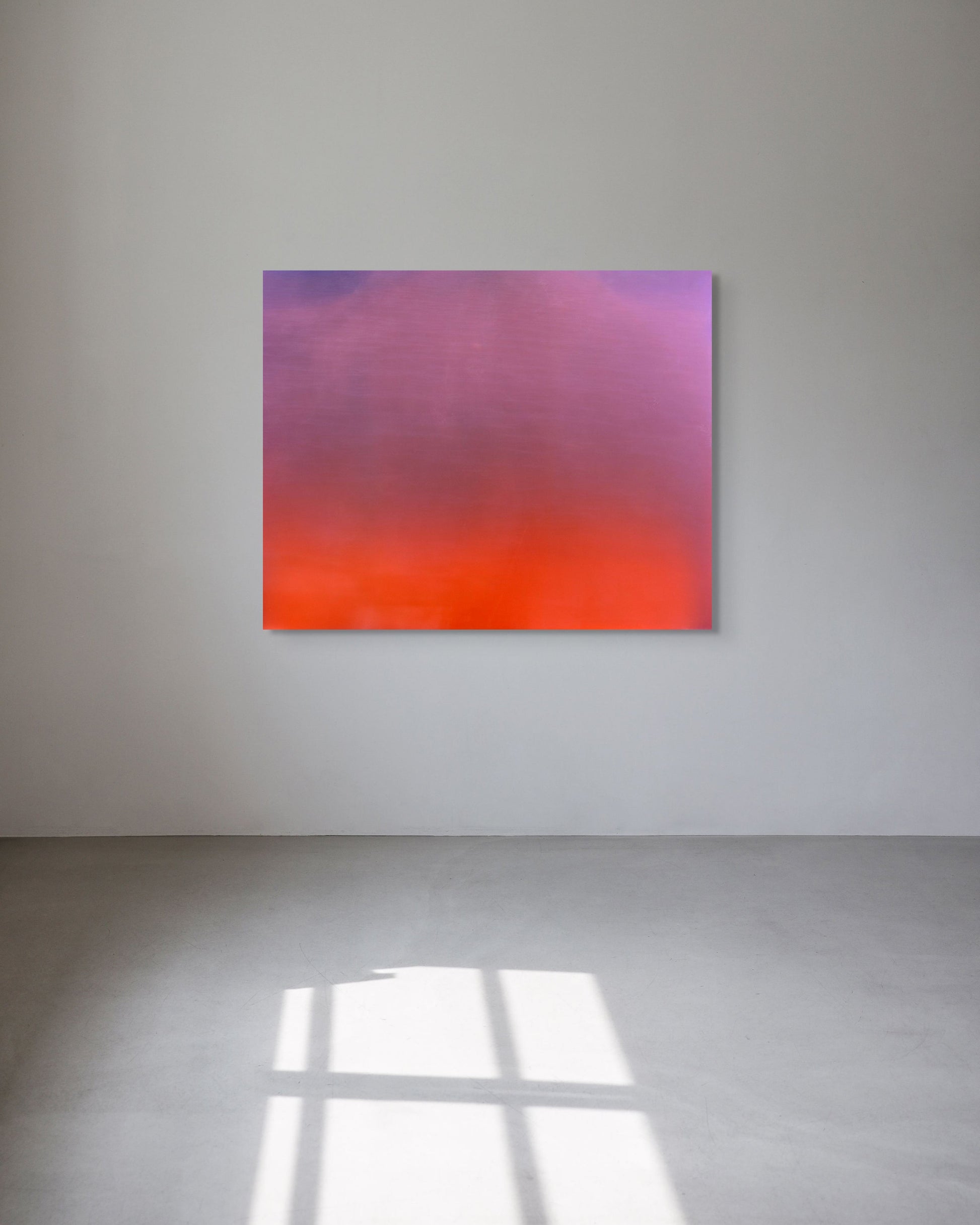 Abstract metal print with pink and orange gradient on a white wall