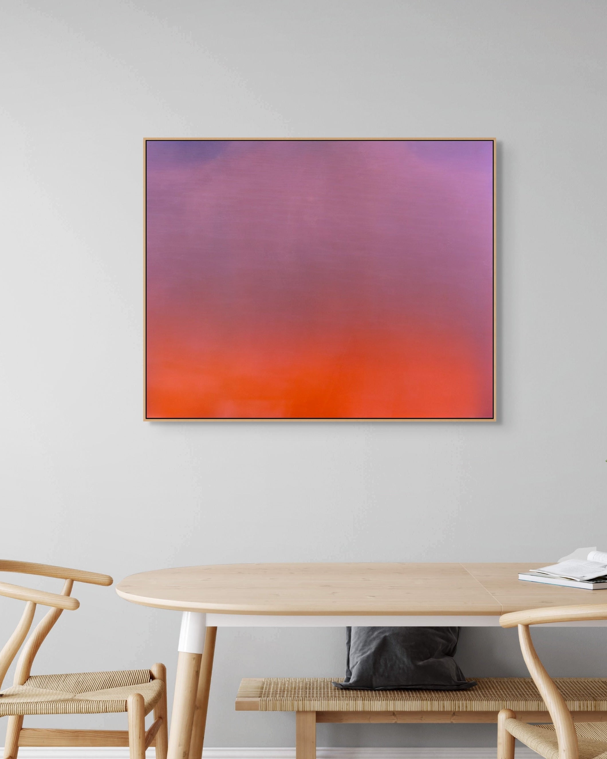 Abstract print on a wall above a dining table with chairs.