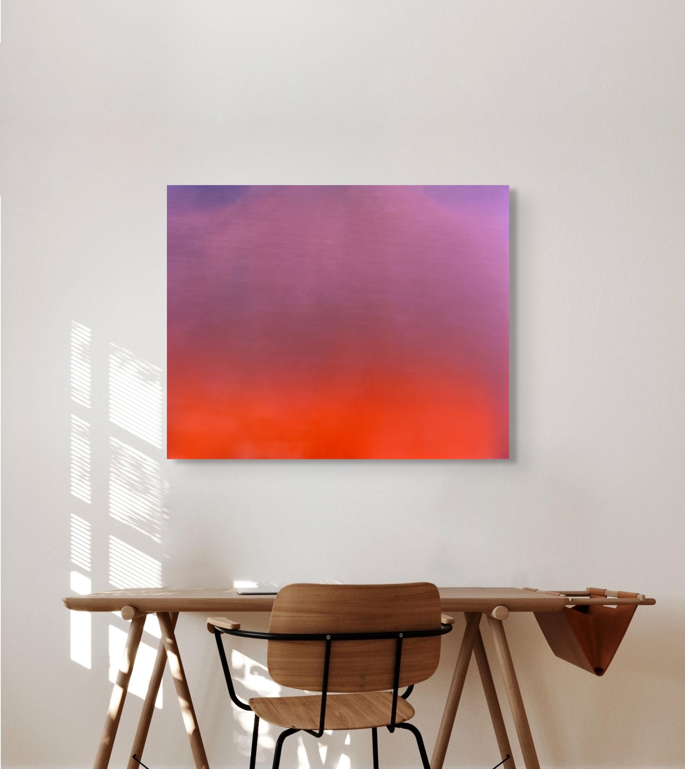 Abstract metal print on a wall above a wooden desk with a chair.