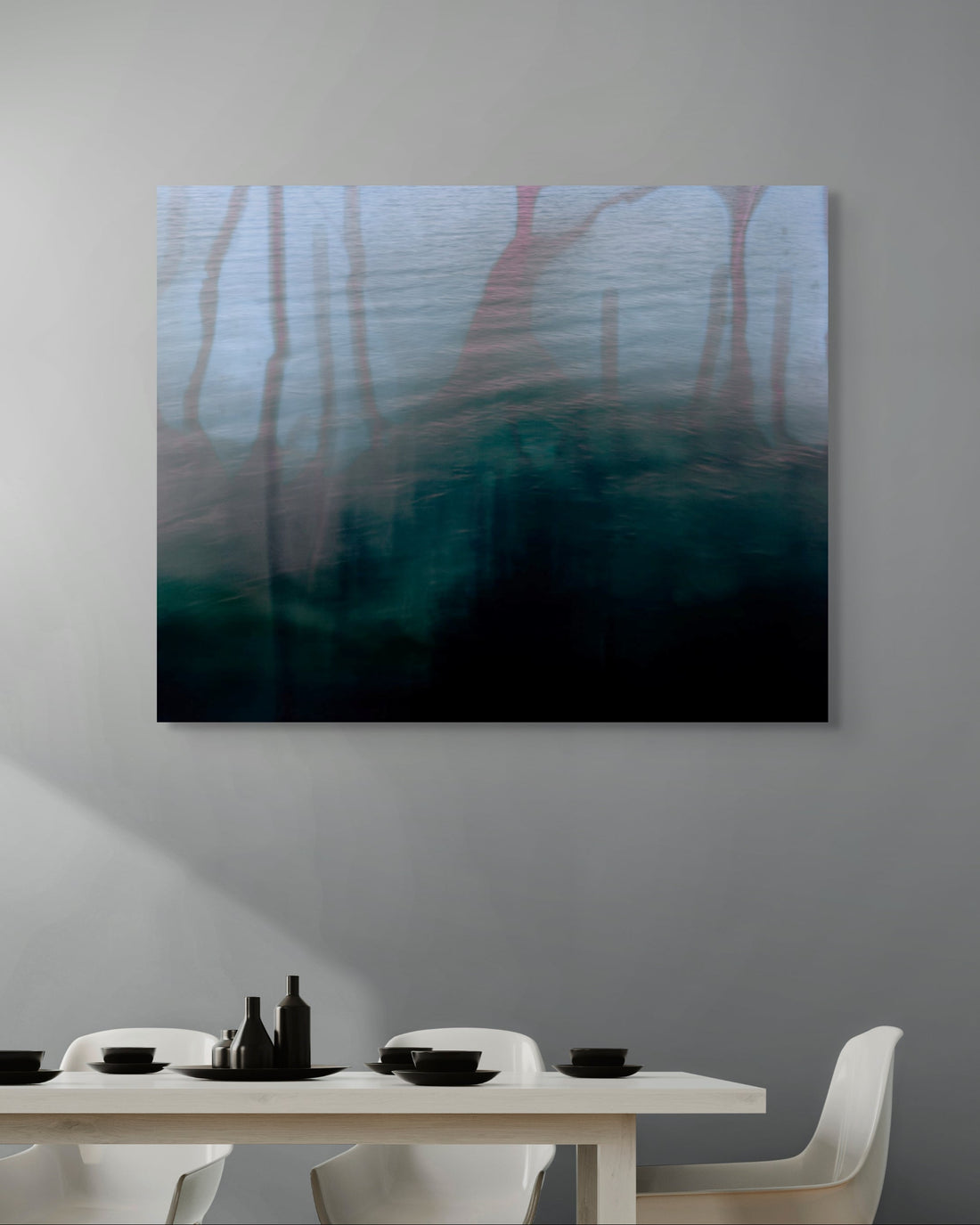 Abstract metal print on a wall above a dining table with chairs.