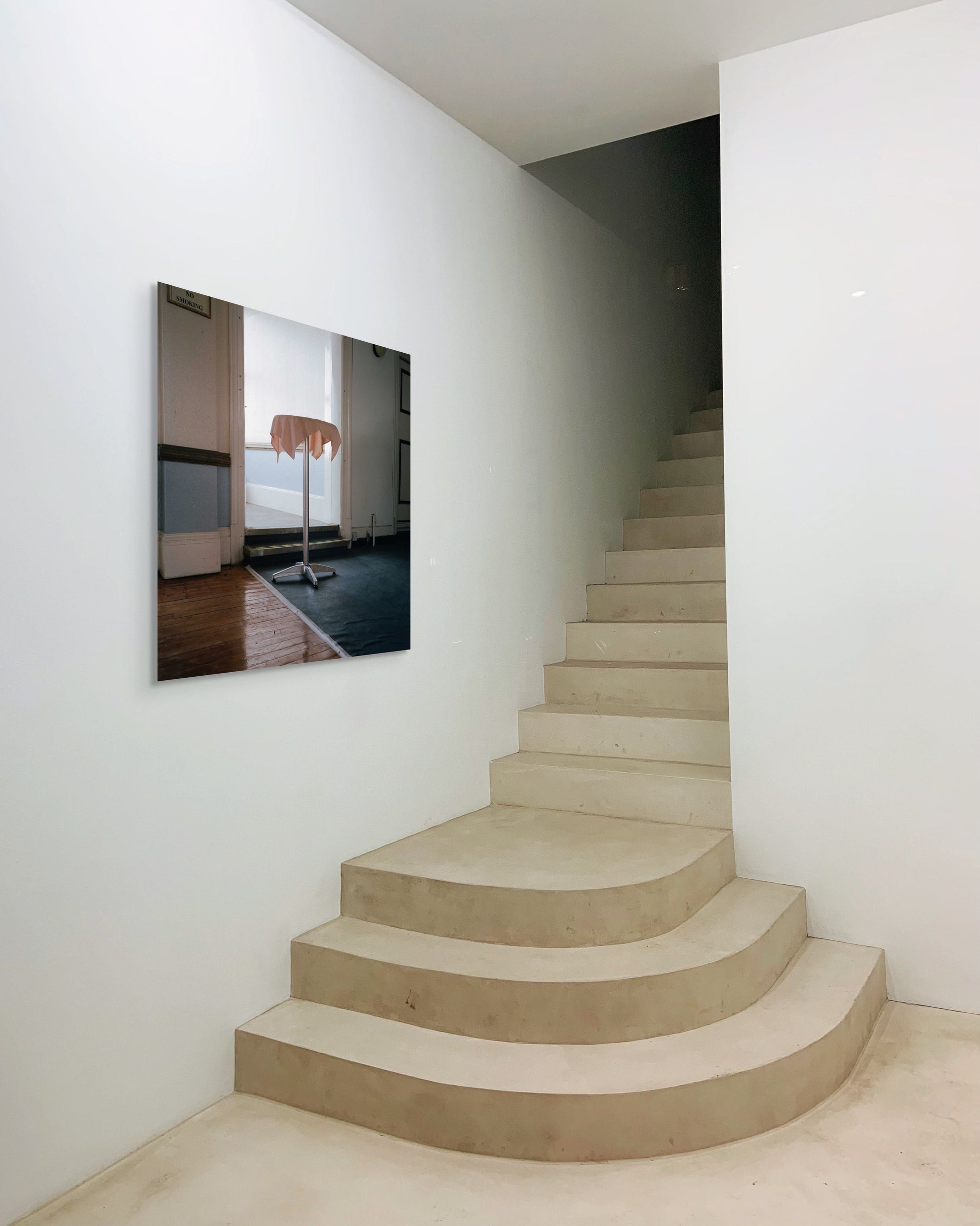 Modern staircase with a large metal print the wall reflecting a room with furniture.