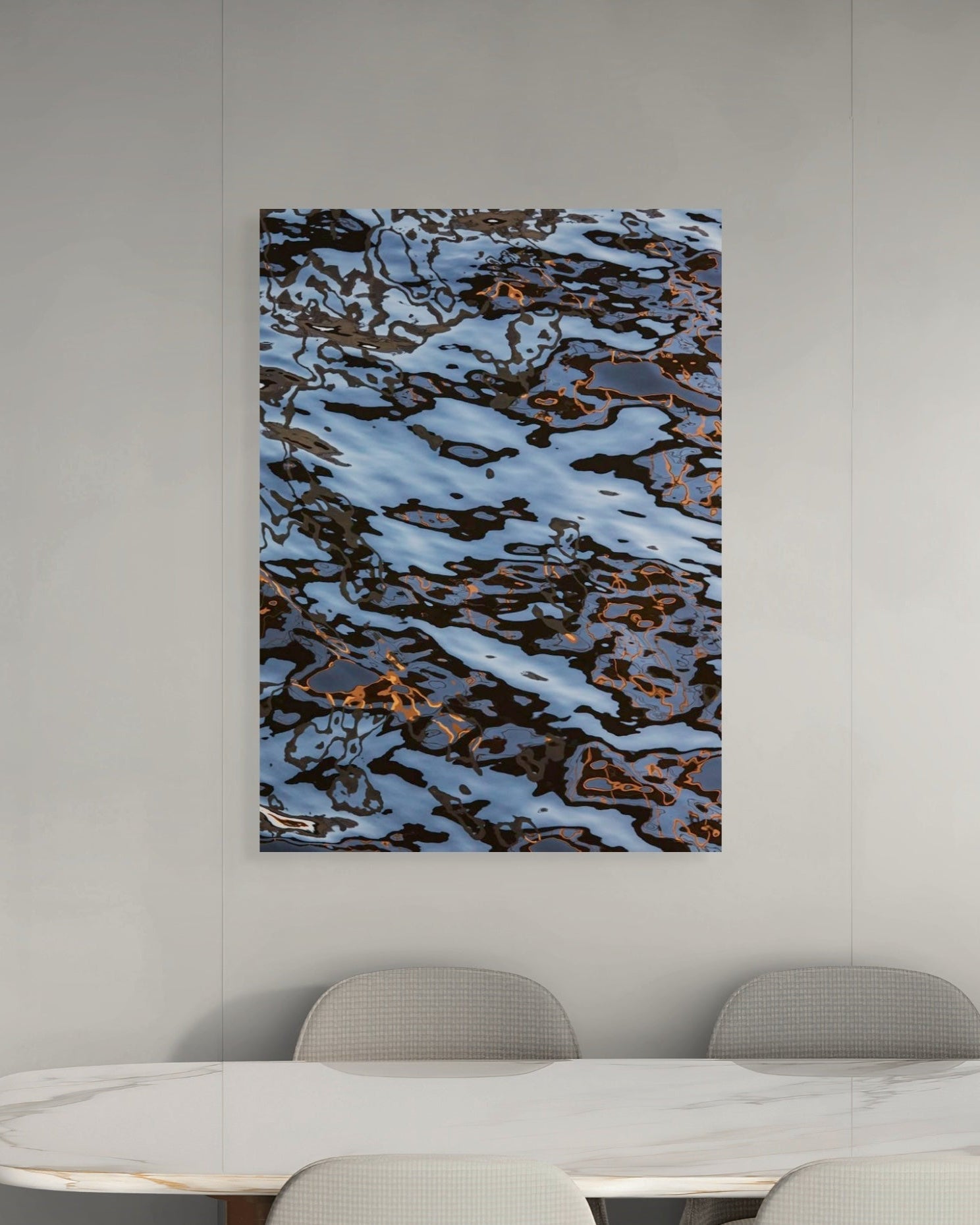 Abstract art piece on a wall above a modern white table with chairs.