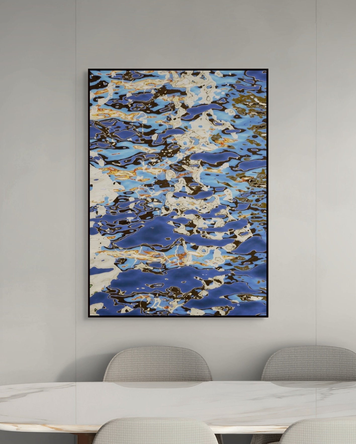 Abstract art piece with blue and white patterns on a gray wall above a dining table.