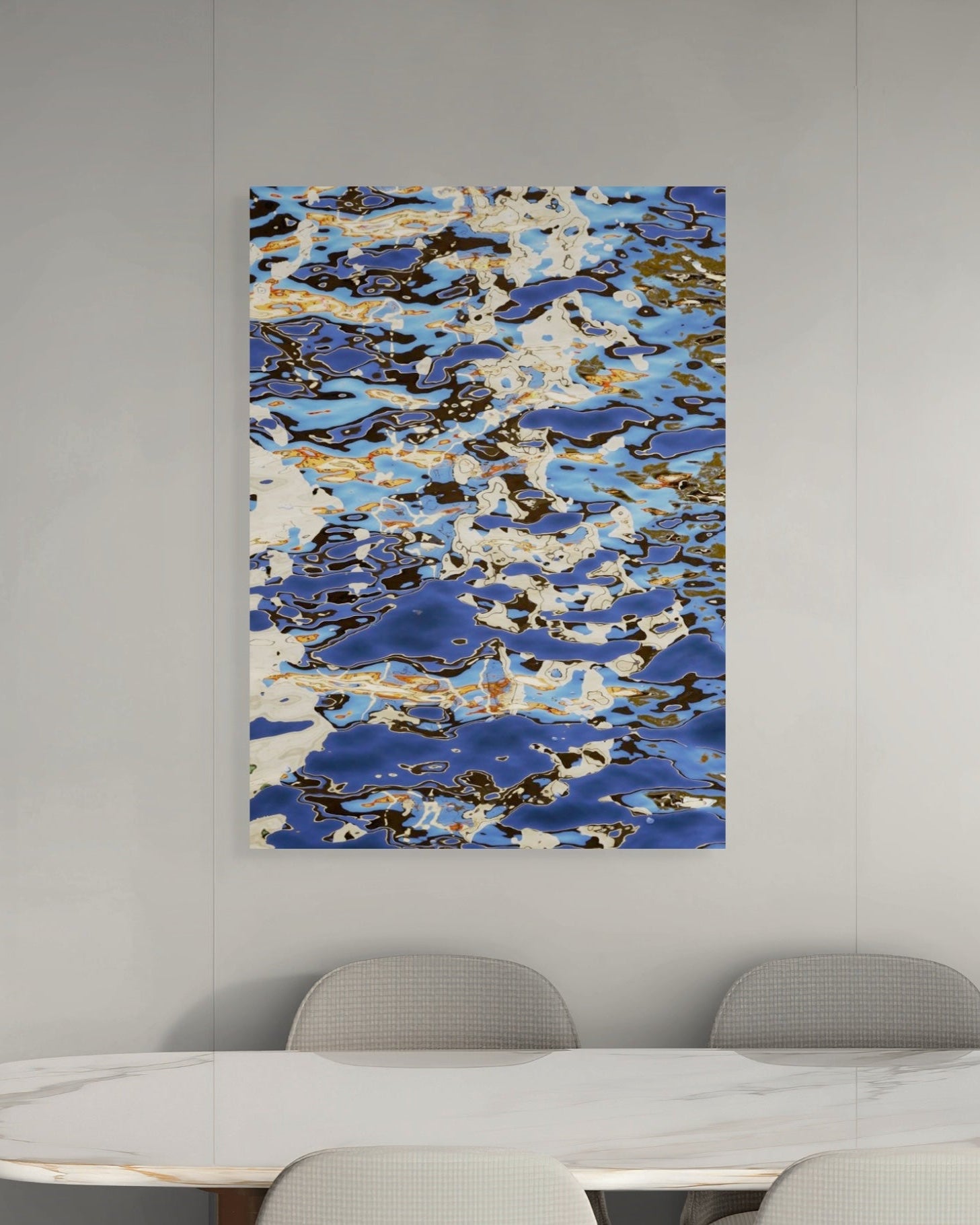 Abstract art piece with blue and white patterns on a gray wall above a table.
