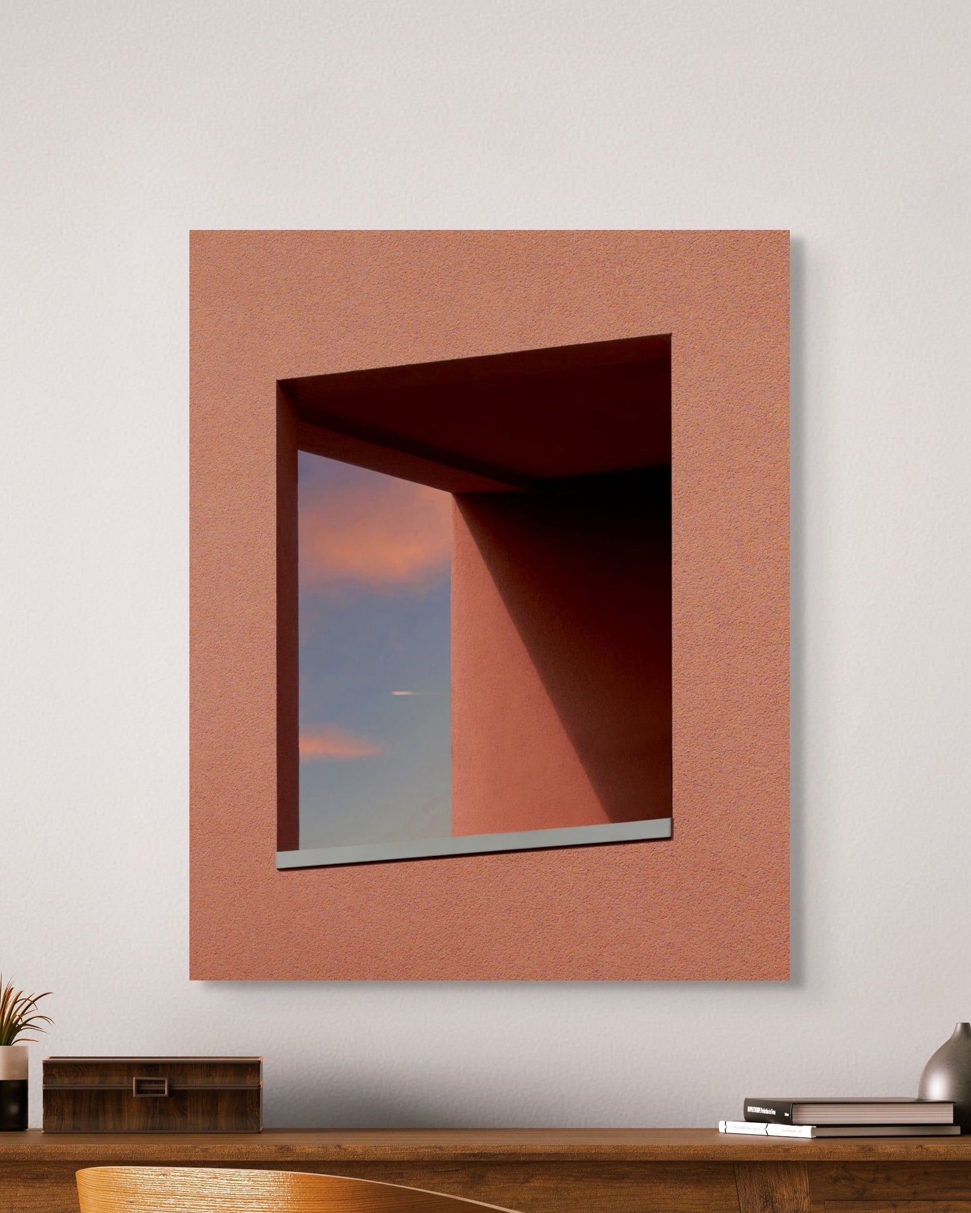 Square metal print on a white wall above a wooden console table.