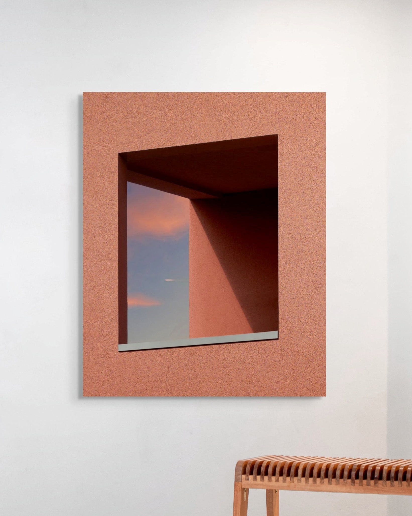 Metal print placed on a white wall with a wooden bench below.