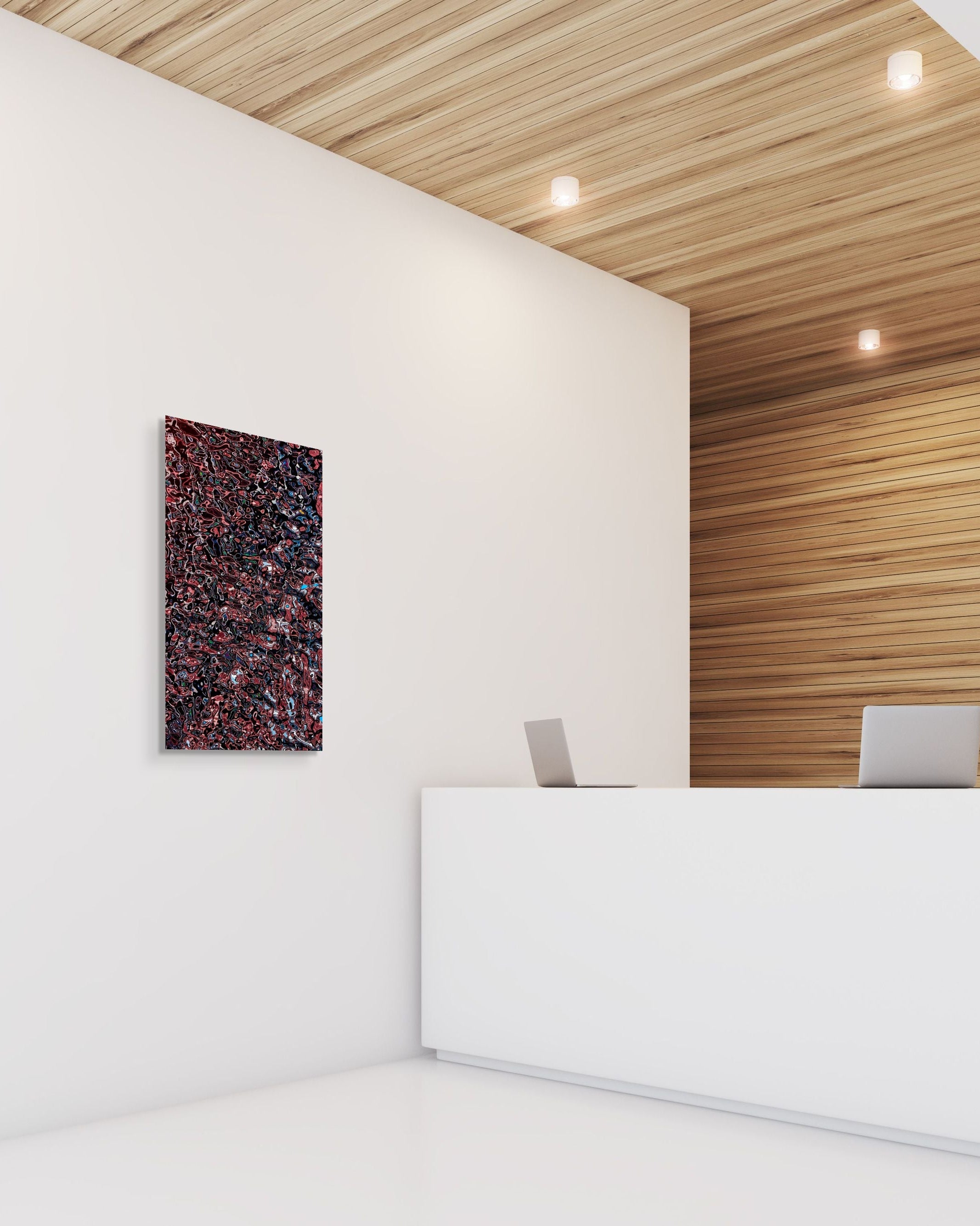 Red, black, and blue abstract metal print displayed on a white wall next to a modern reception desk with wood paneling and soft ceiling lights.