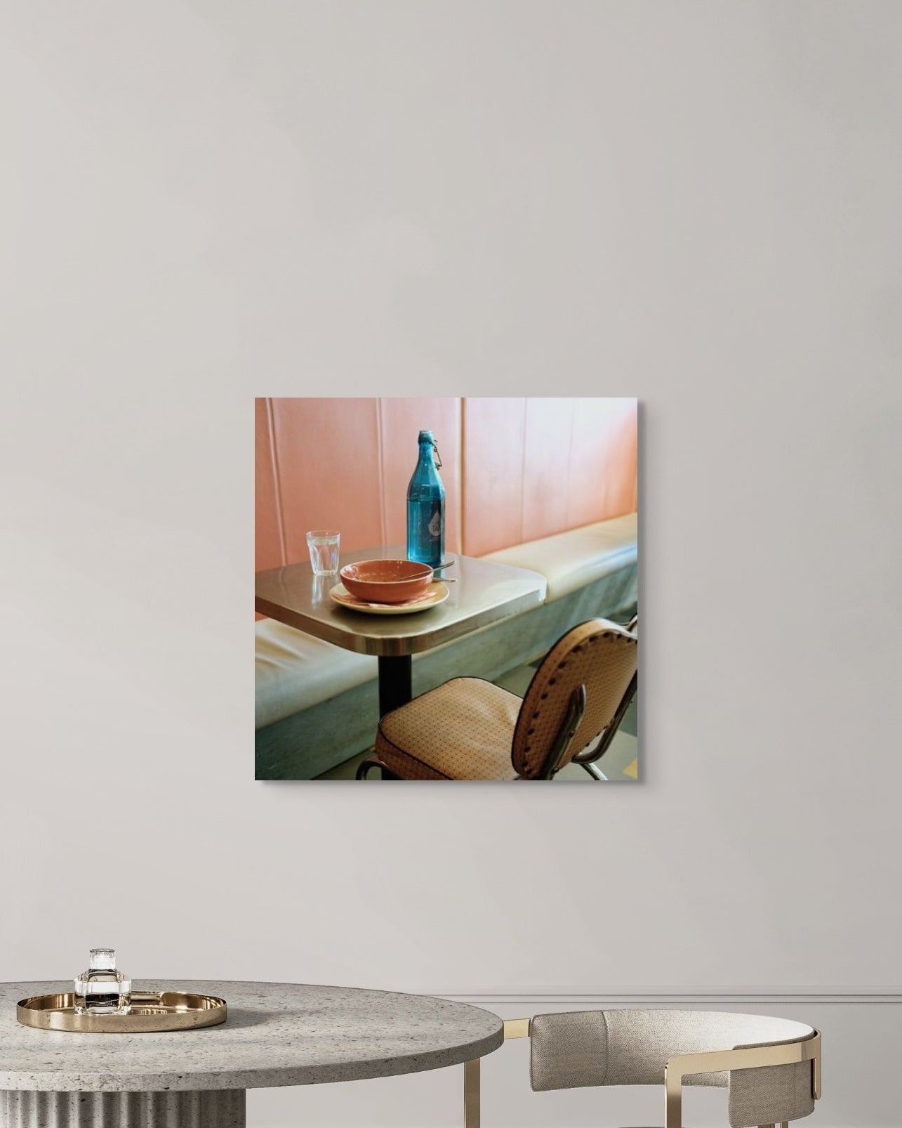 Framed artwork of a dining scene on a wall with a mirror and table below.