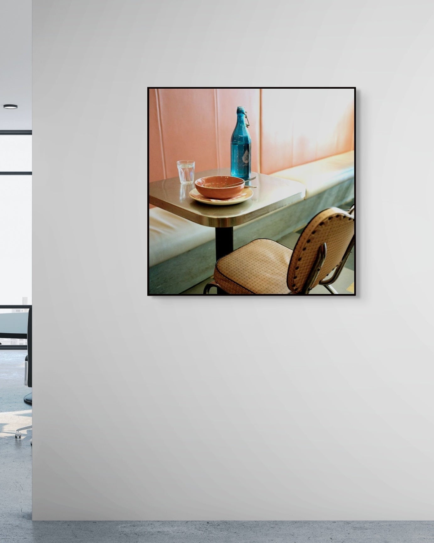 Framed artwork of a dining scene on a wall in an office setting