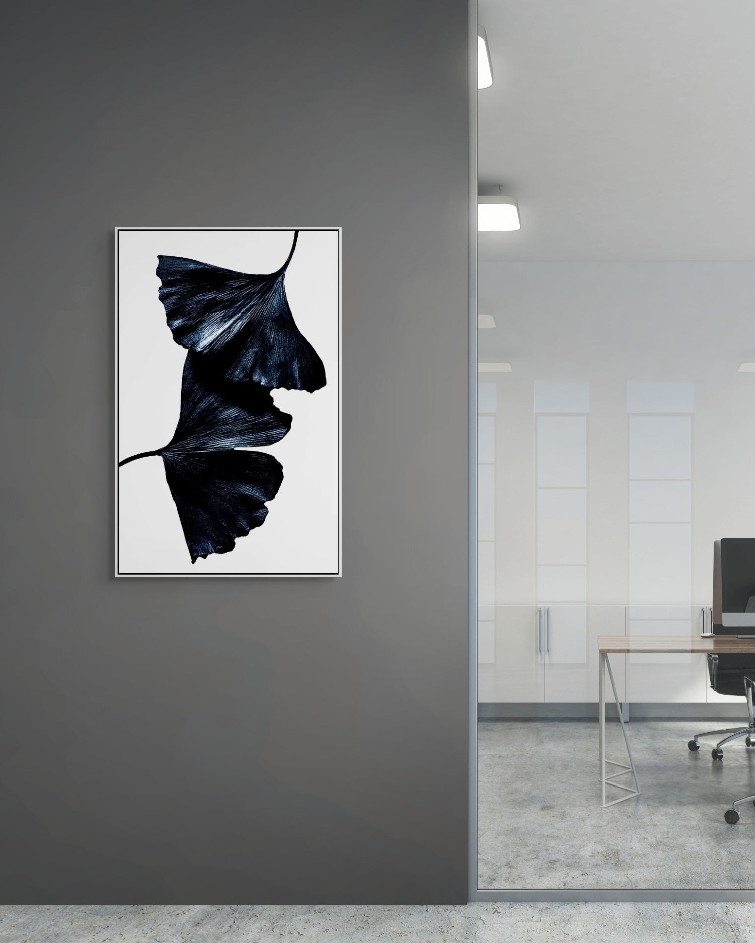 Framed artwork of a black leaf on a gray wall in an office setting