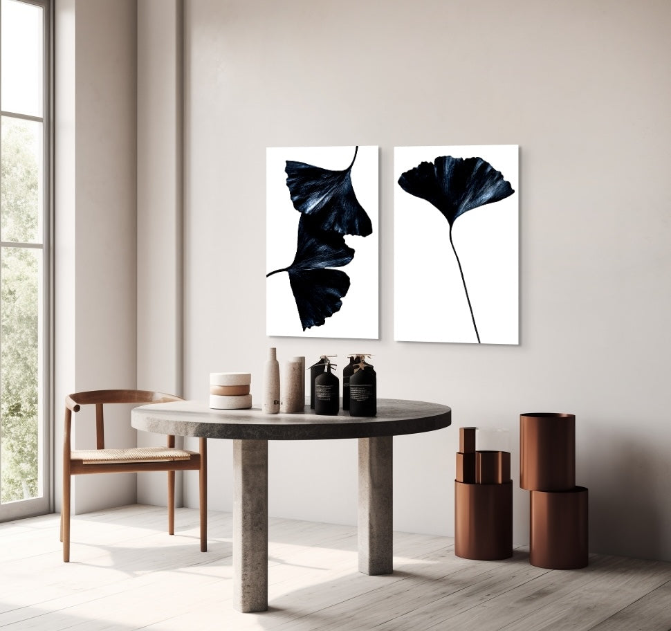 Modern interior with a round wooden table and chairs, featuring two abstract leaf metal prints on the wall.