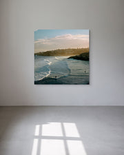 Metal print of a beach scene hanging on a white wall.