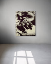 Metal print of two hands on a textured surface in a minimalistic room with sunlight casting shadows.