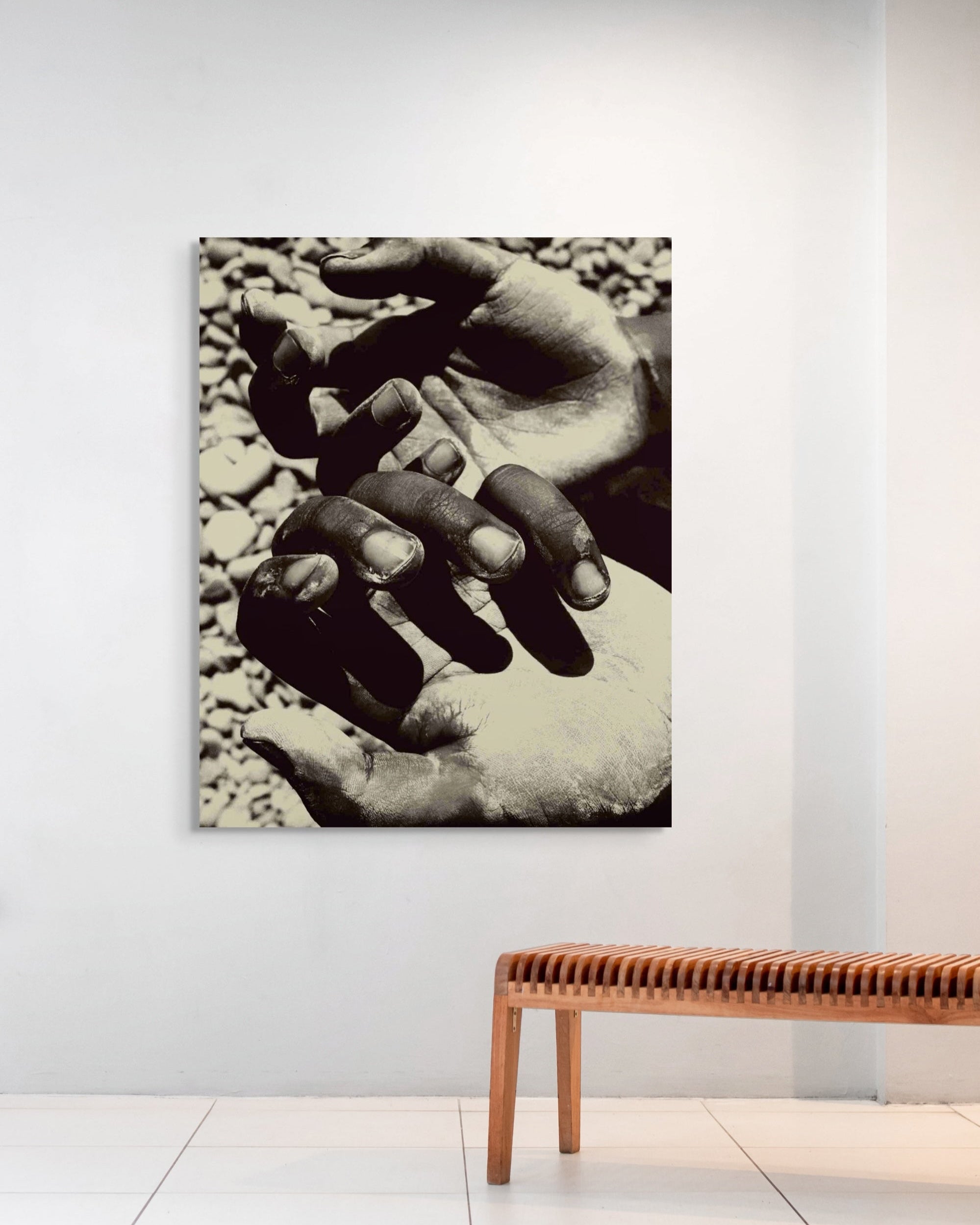Metal print of two hands on pebbles in a minimalistic room with a wooden bench.