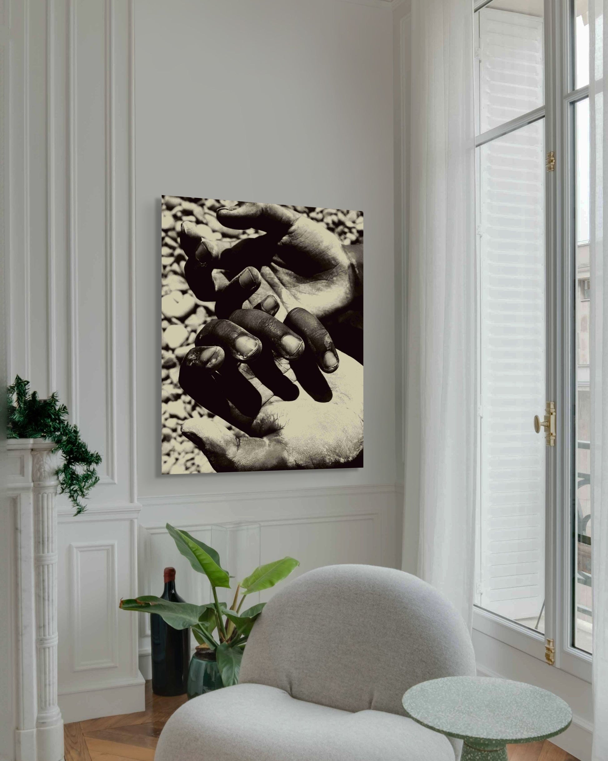 Metal wall art of hands on a wall in a room with a chair and plants. 