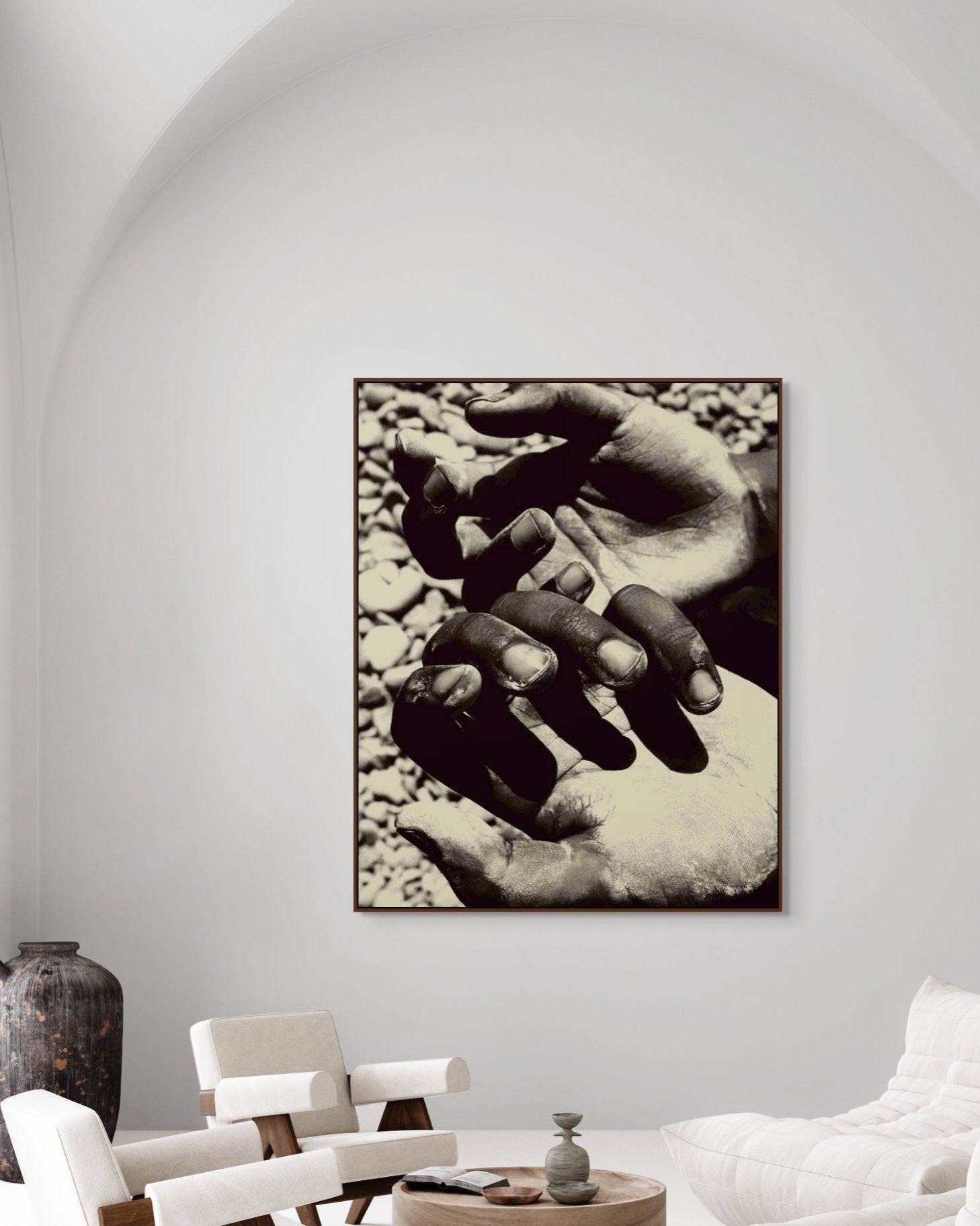 Framed black and white artwork of two hands on a wall in a modern living room.