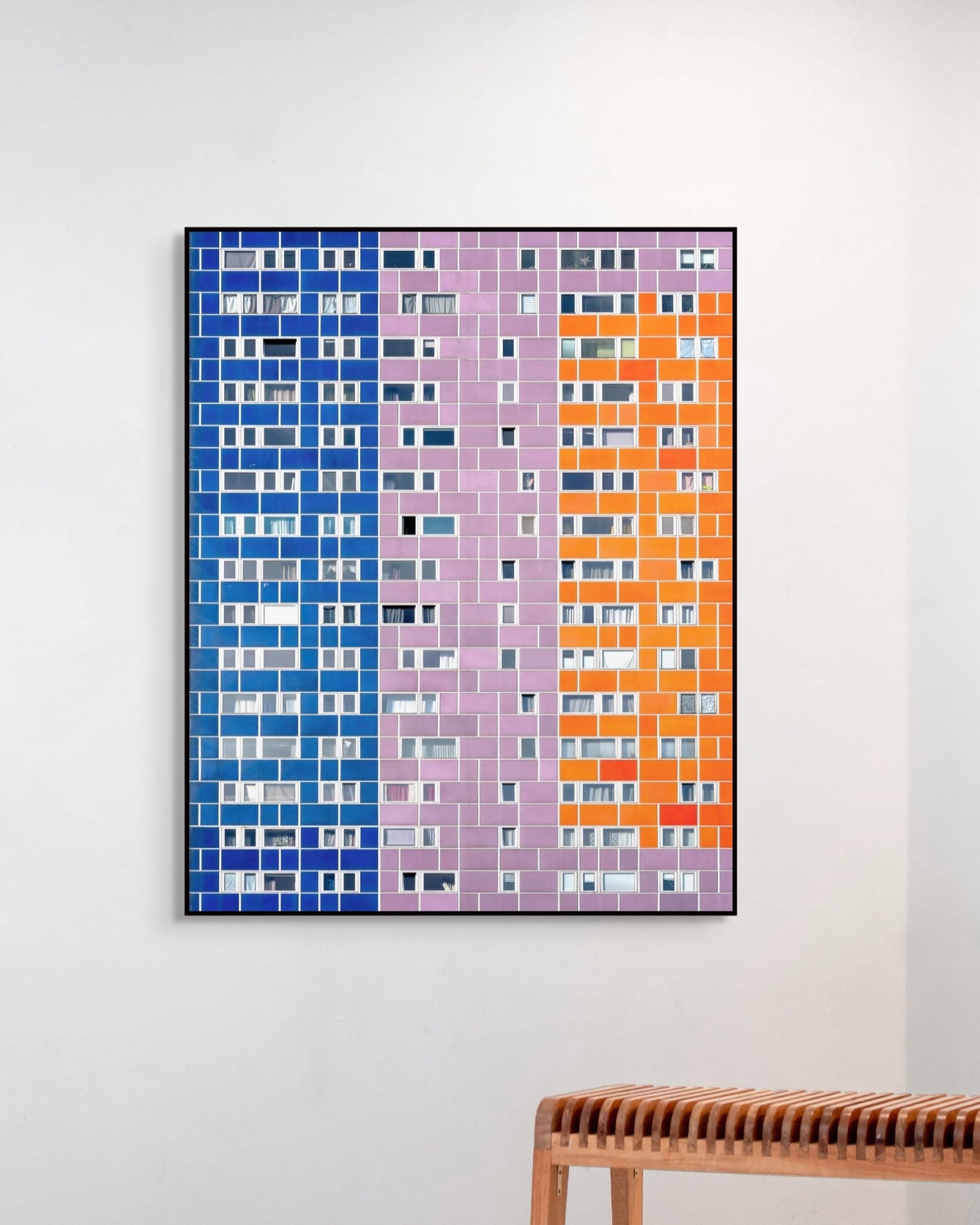 Framed abstract artwork with blue, purple, and orange vertical stripes on a white wall.