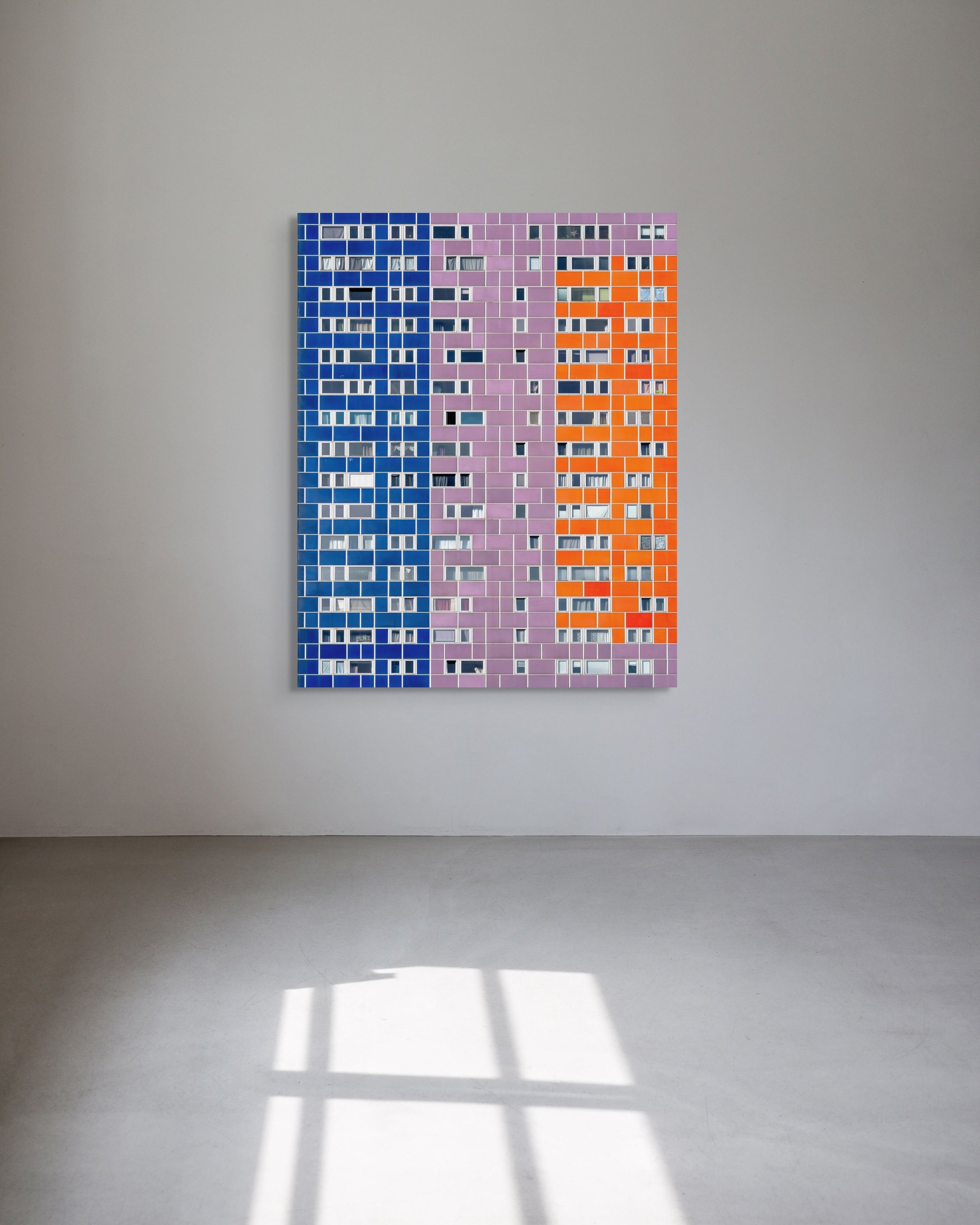 Abstract metal print of a vertical building in blue, pink, and orange on a white wall.