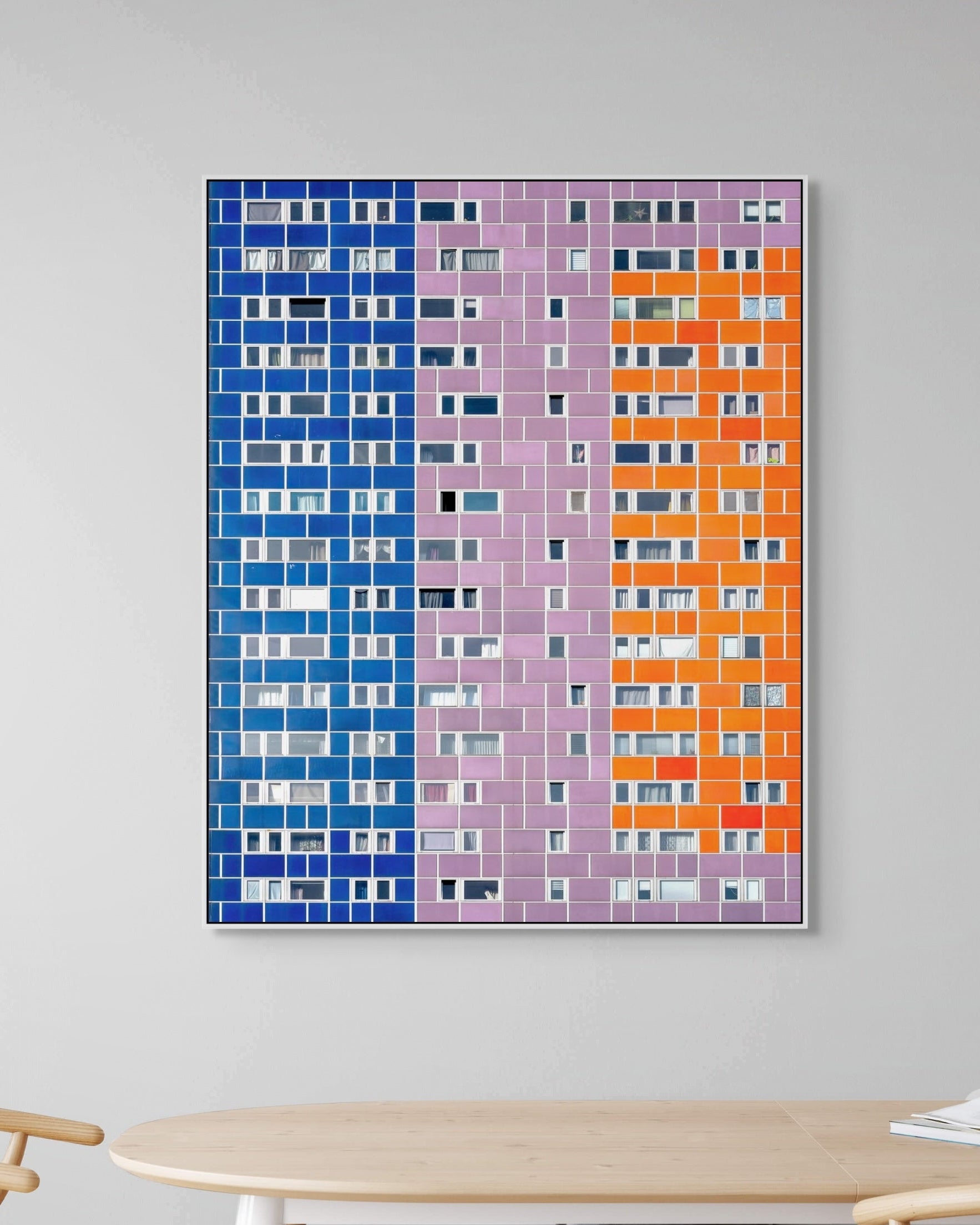 Colorful abstract wall art on a gray wall with a wooden table and chair in the foreground.