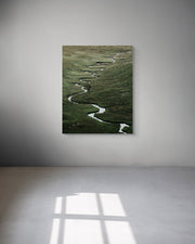Metal print of a landscape with a winding path on a white wall.
