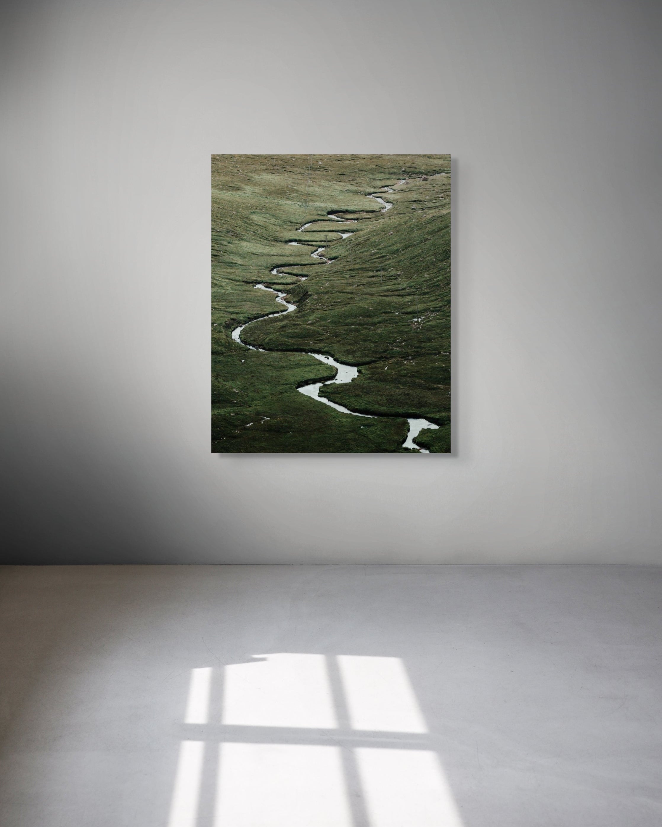 Metal print of a landscape with a winding path on a white wall.