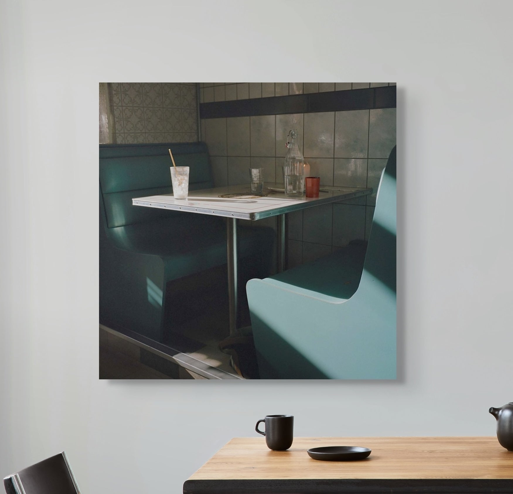 Framed photograph of a diner interior with booth seats and a table on a light gray wall.