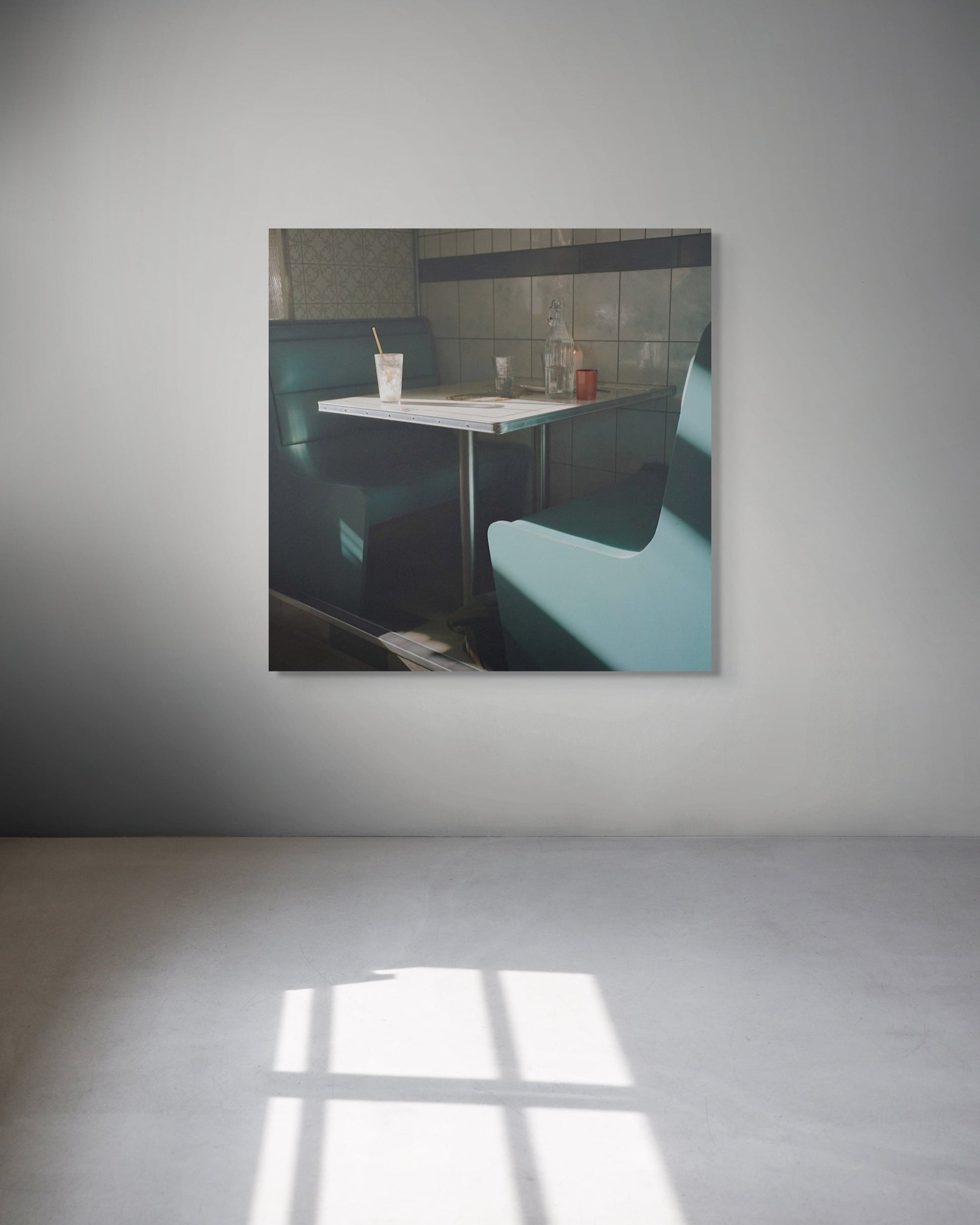 Framed photograph of a diner interior with a table and booths on a gray wall.