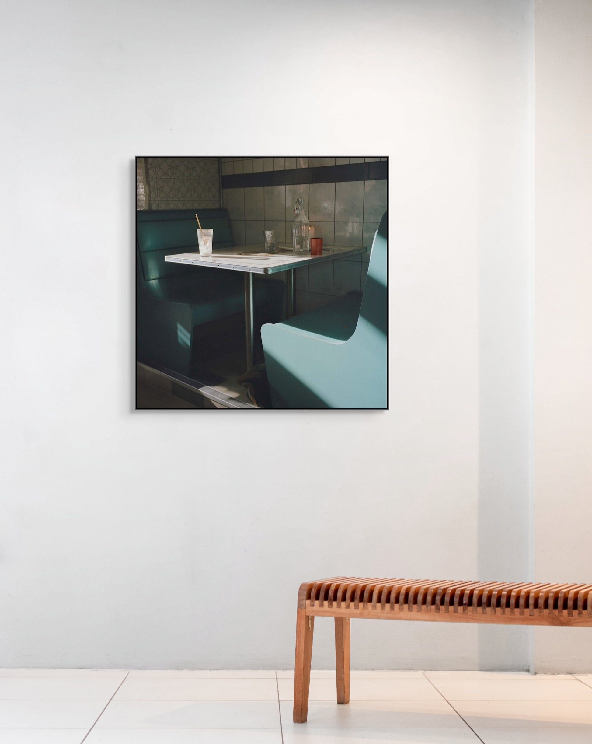 Framed photograph of a restaurant interior with a table and chairs on a white wall.