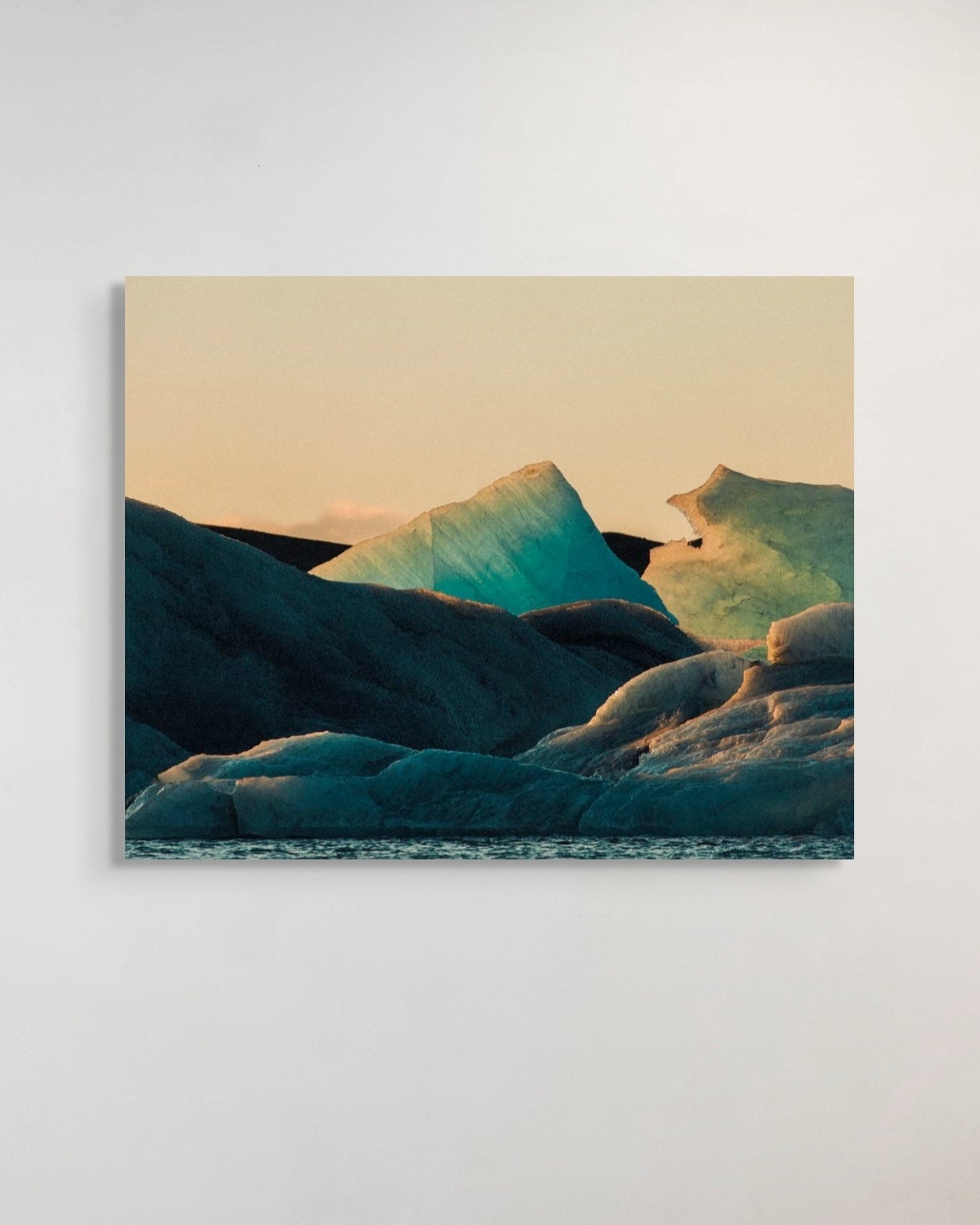 Metal print of a mountain landscape with a warm color palette on a white wall.