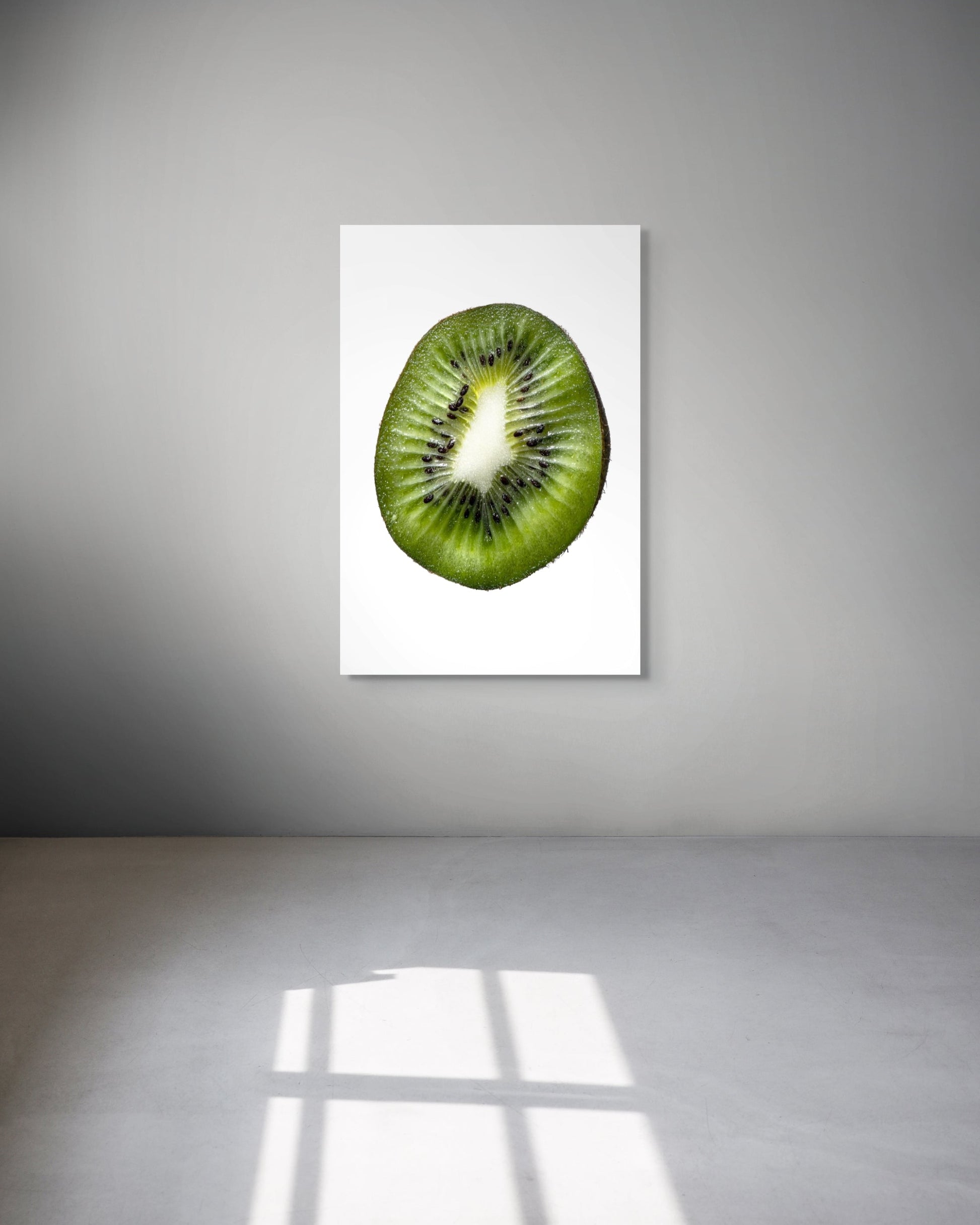 Framed picture of a kiwi fruit on a white wall.